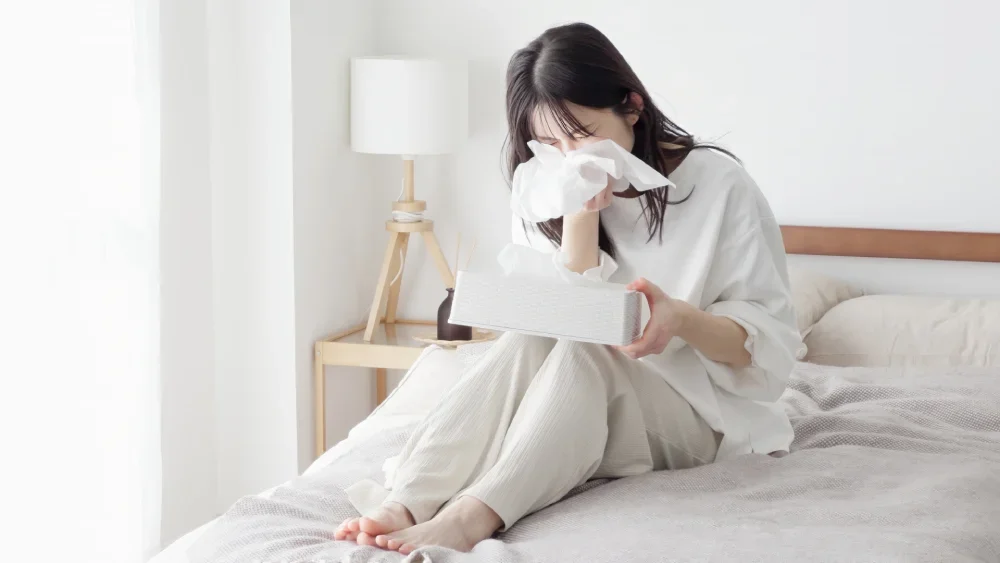 Woman with allergic rhinitis blowing her nose.