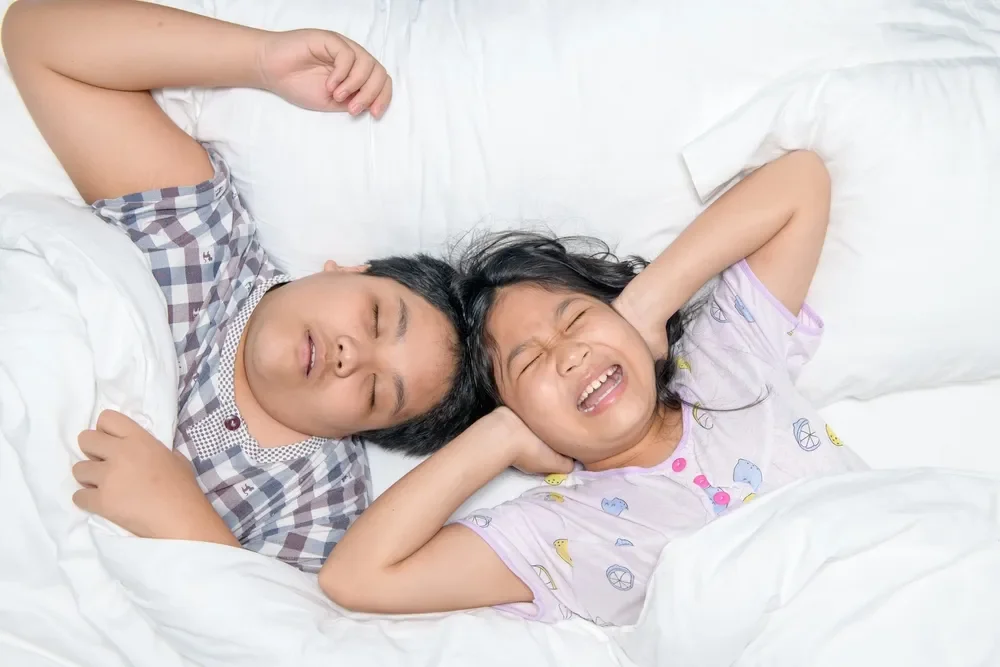 Boy snoring in his sleep and girl covering her ears