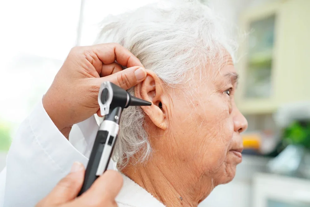 An ENT doctor examining an elderly woman for hearing loss.