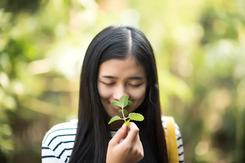 A woman smiling contentedly while smelling a plant