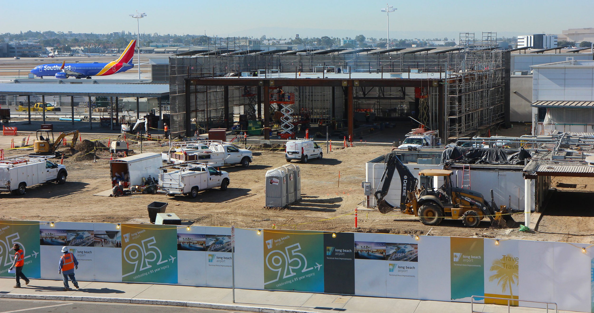Construction site with partial building. Airplane on taxiway to rear left.