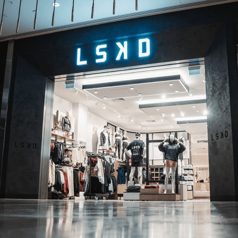 Clothing store entrance with mannequins displaying athletic apparel and racks of clothes inside.