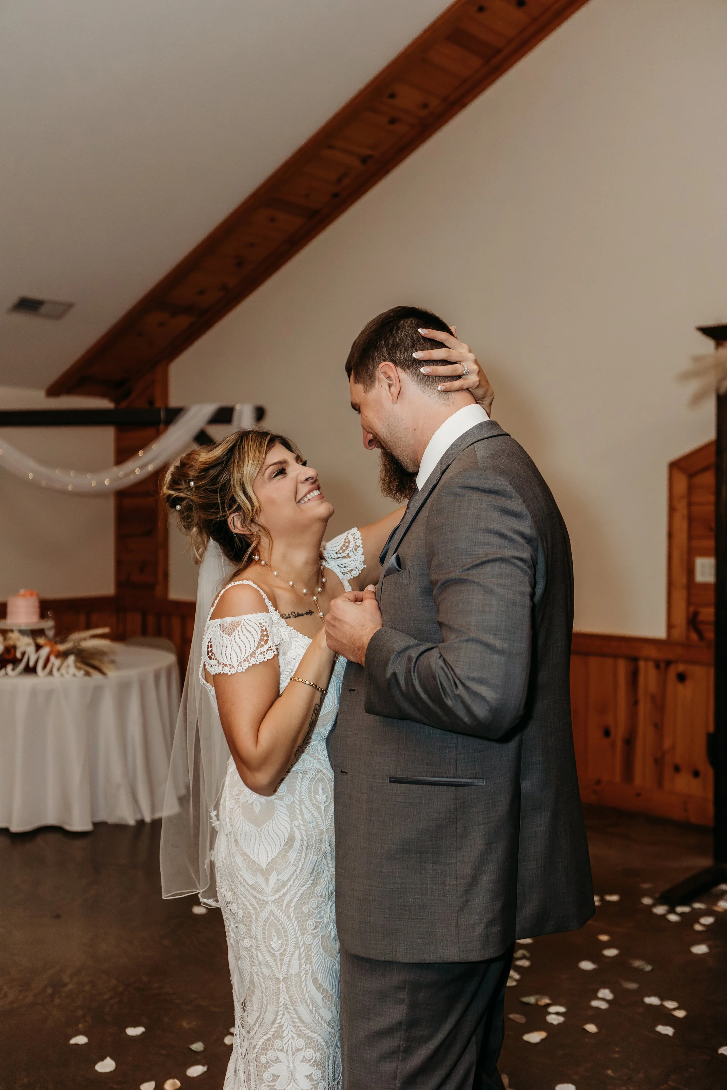 A bride and groom share a dance at their wedding reception, smiling and gazing into each other's eyes.