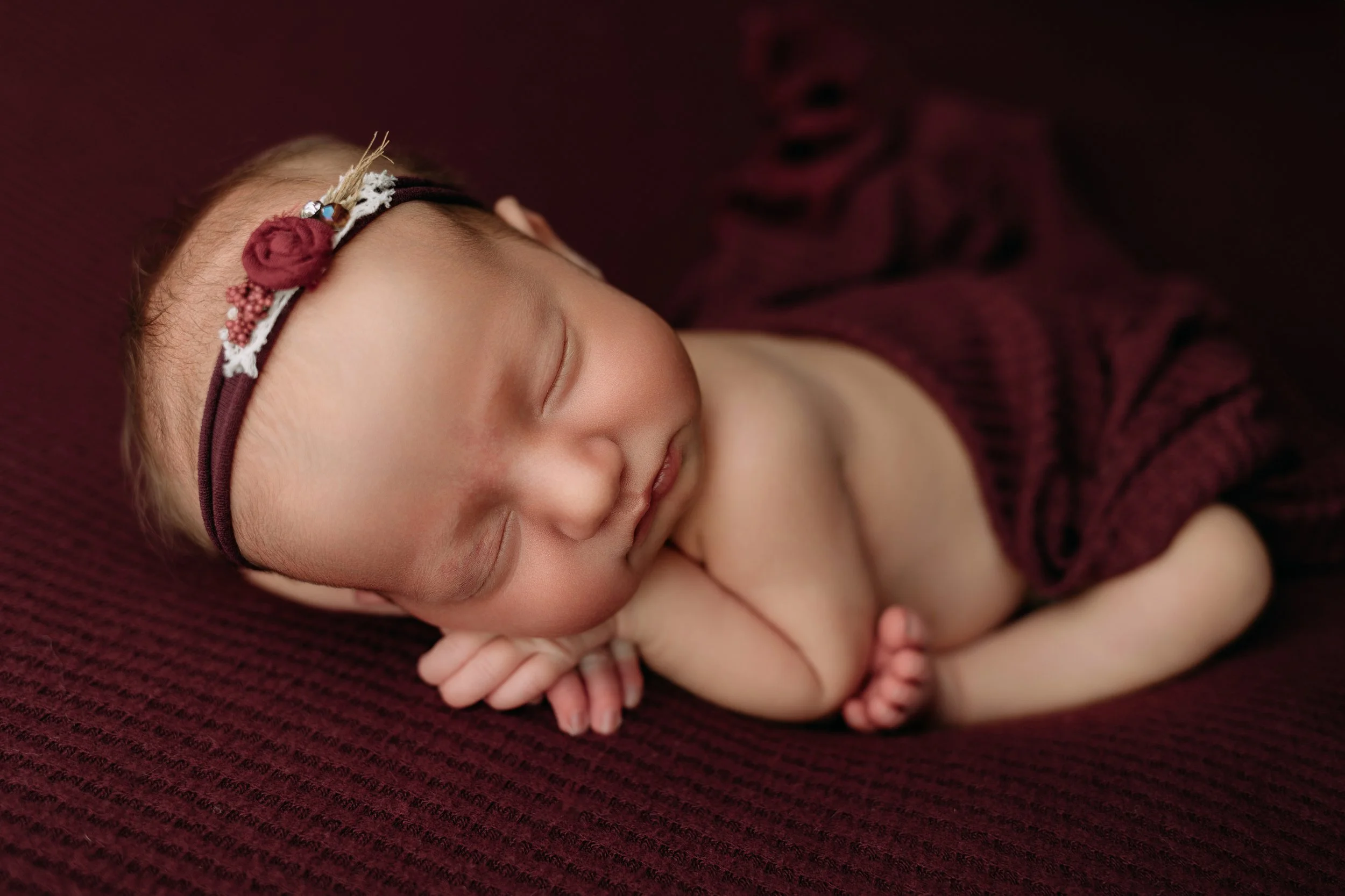 newborn-baby-girl-sleeping-on-a-burgundy-blanket.jpg