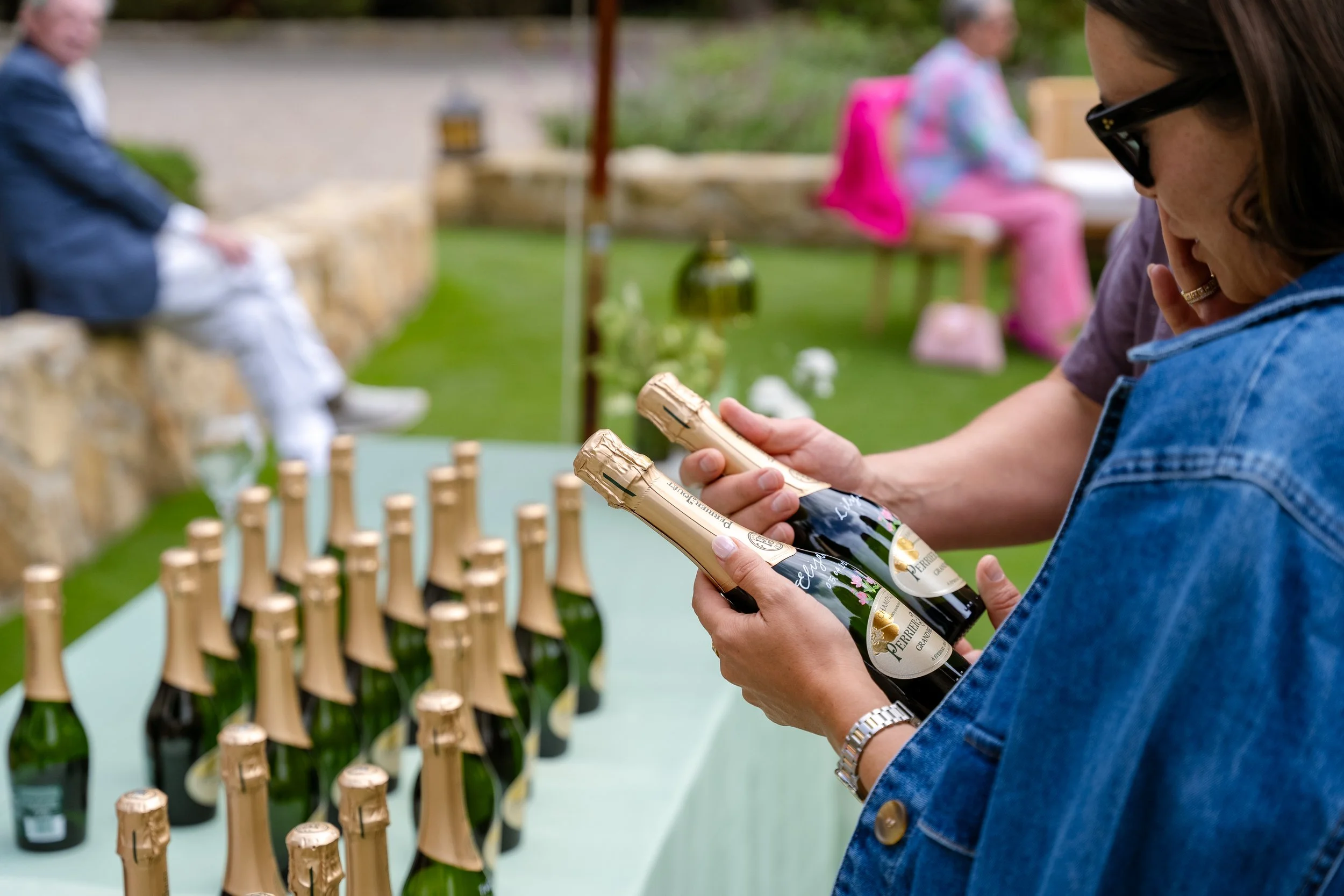 Hand painted with calligraphy Perrier-Jouët champagne bottle personalized live with floral artwork at a garden party.