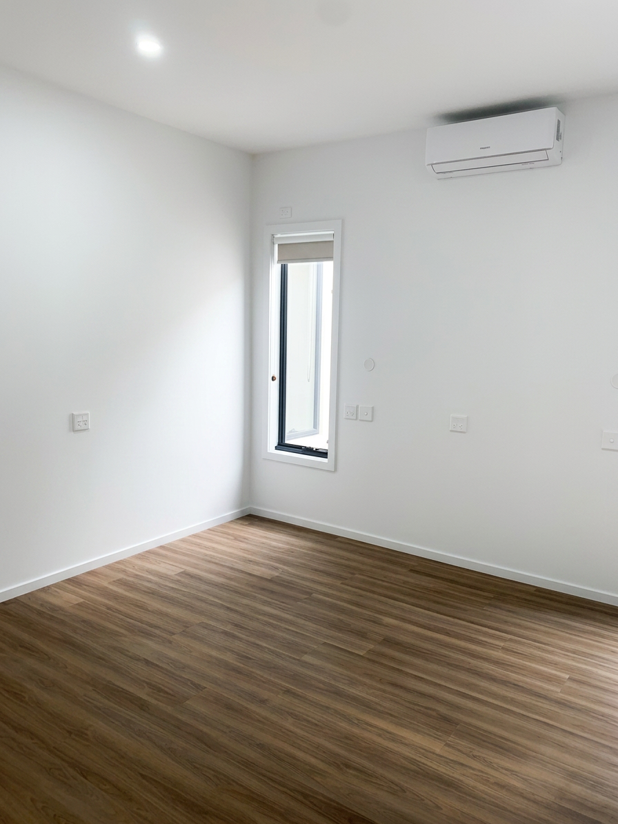 Output_an_image_of_the_provided_room_photo_with_a_slightly_adjusted_more_balanced_wide_angle_perspective_so_the_walls_appear_straighter_and_the_space_feels_more_open._Increase_overall_brightness_and_enhance_soft_natural_daylight_coming_thro.png