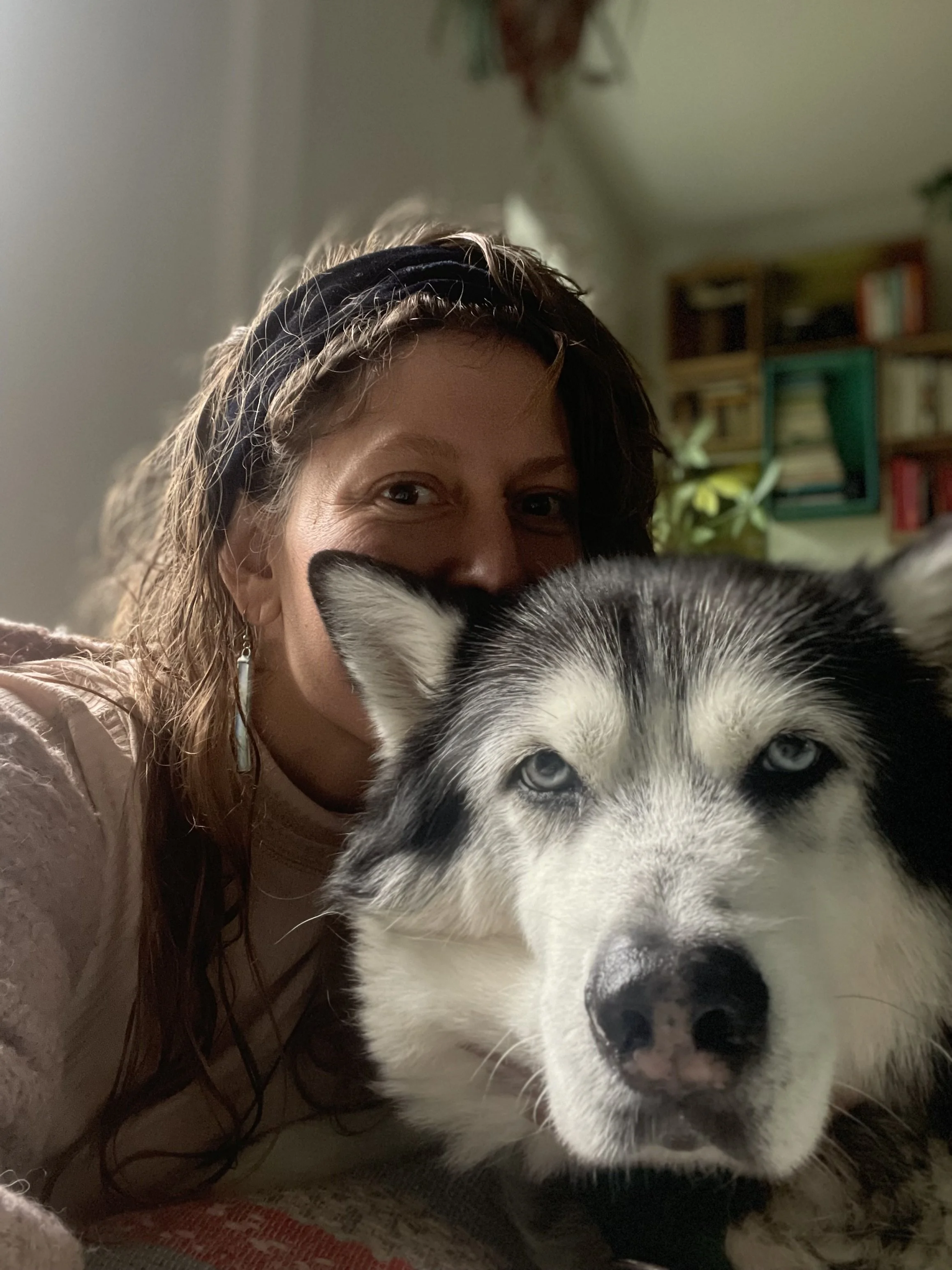 A husky with a person smiling behind him.