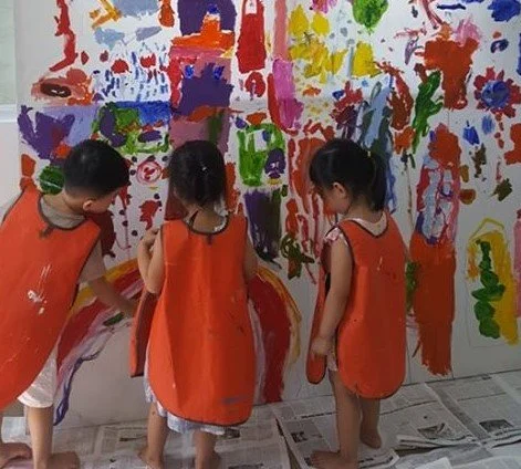 Three children painting together on a giant canvas