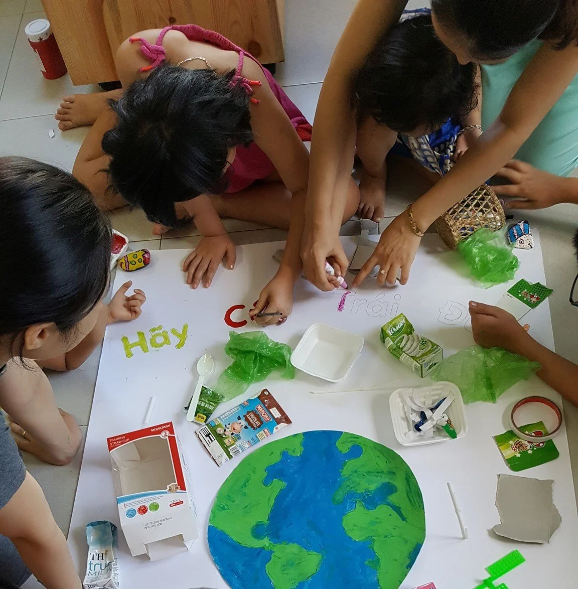 A group of children and an adult creating a craft project on a table