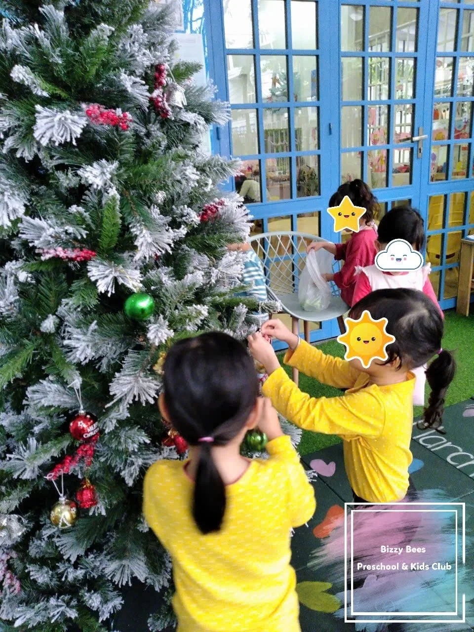 Children decorating a Christmas tree with ornaments at Bizzy Bees Preschool & Kids Club.