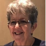 A smiling woman with short gray hair and glasses