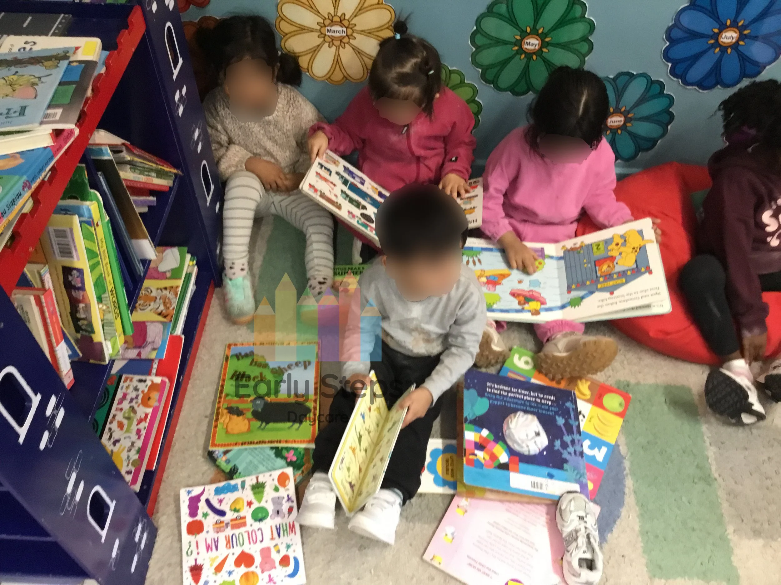 Group of young children sitting together reading books at nursery to support communication, language development and early literacy.