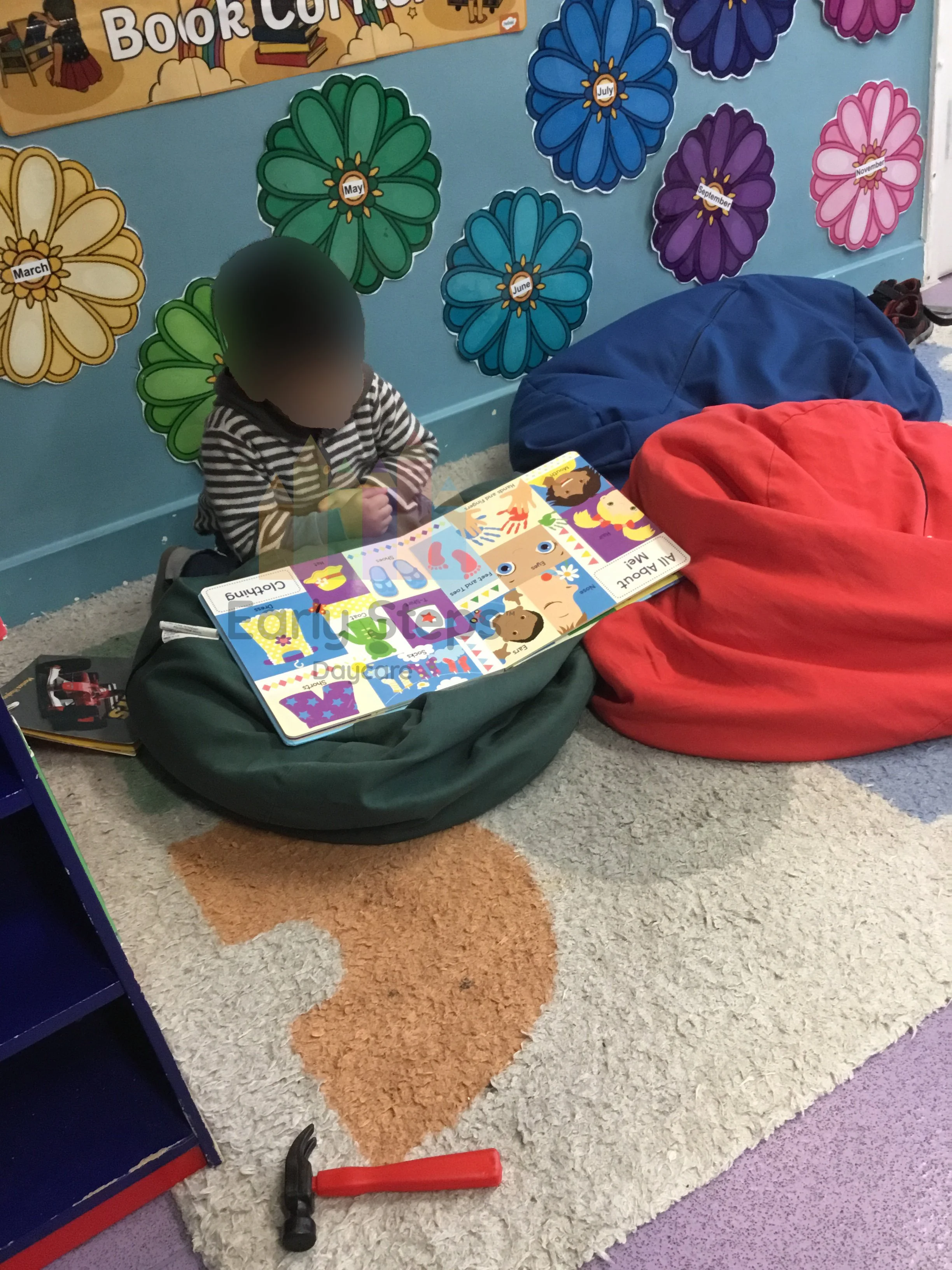 Young child deeply engaged in reading a book at nursery, supporting communication, concentration and early literacy development.