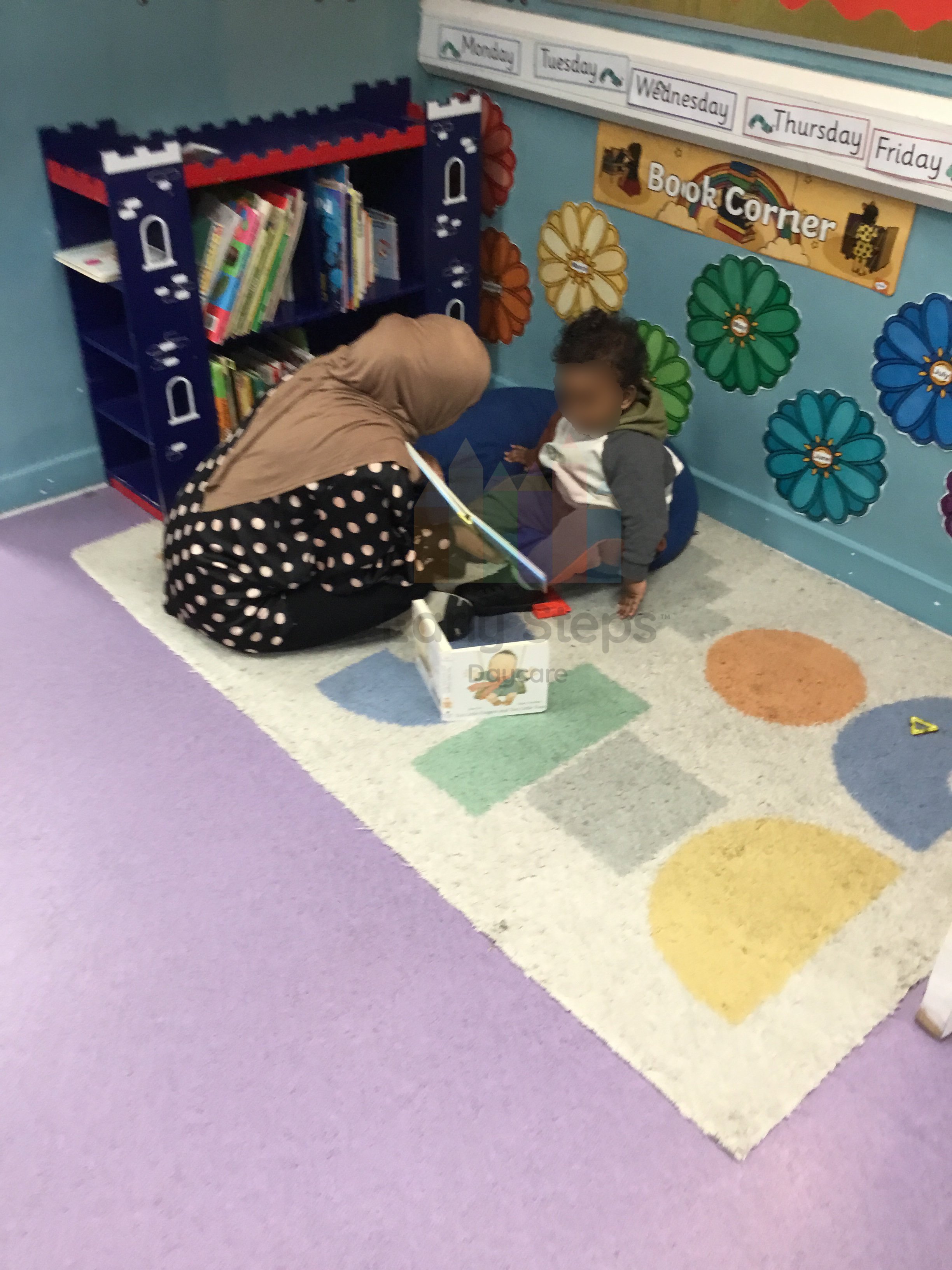 Nursery practitioner reading a book to an excited infant to support early communication, listening skills and language development.