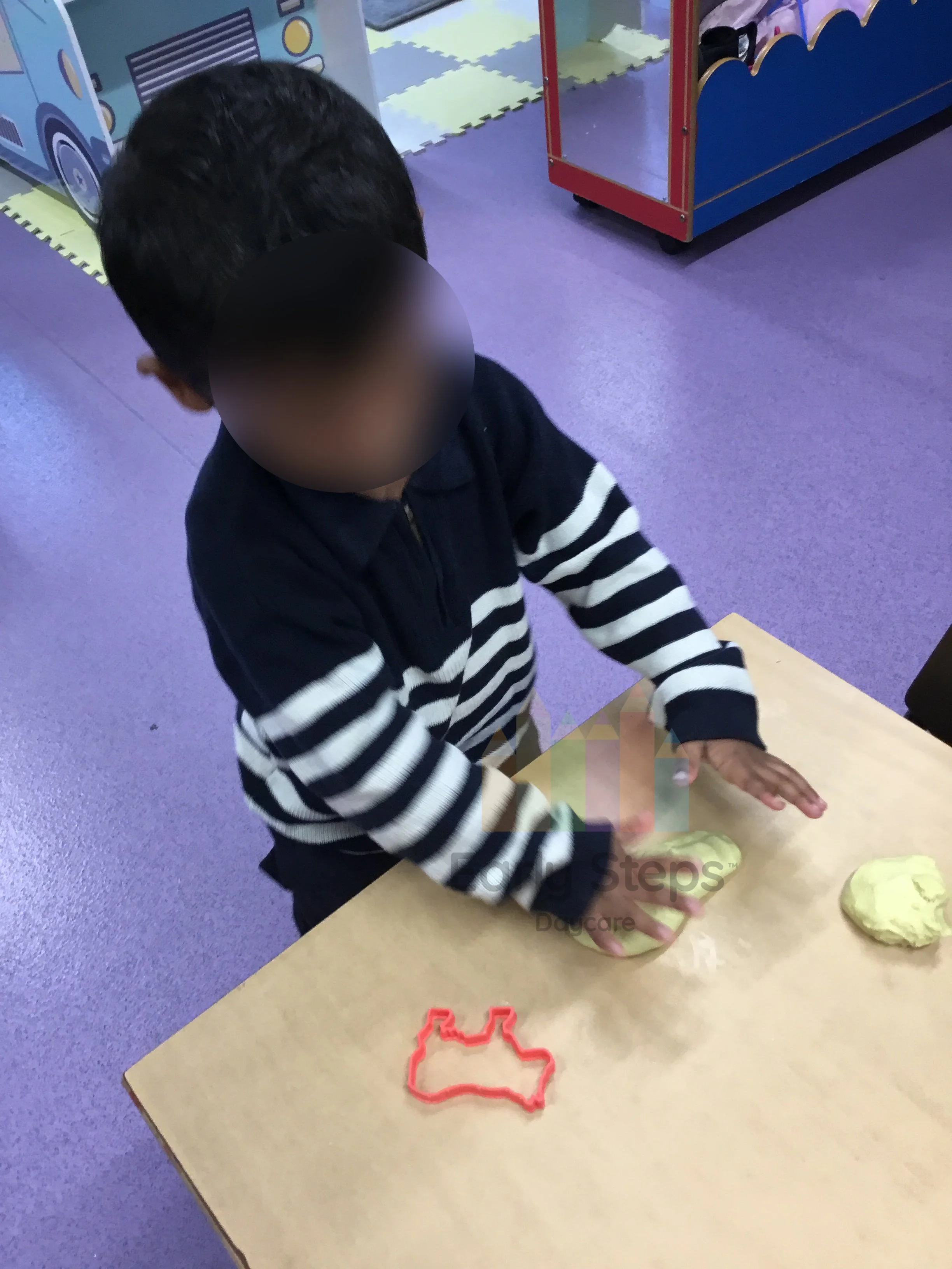 Young child playing with playdough and shape cutters at nursery to support fine motor skills and hand coordination.