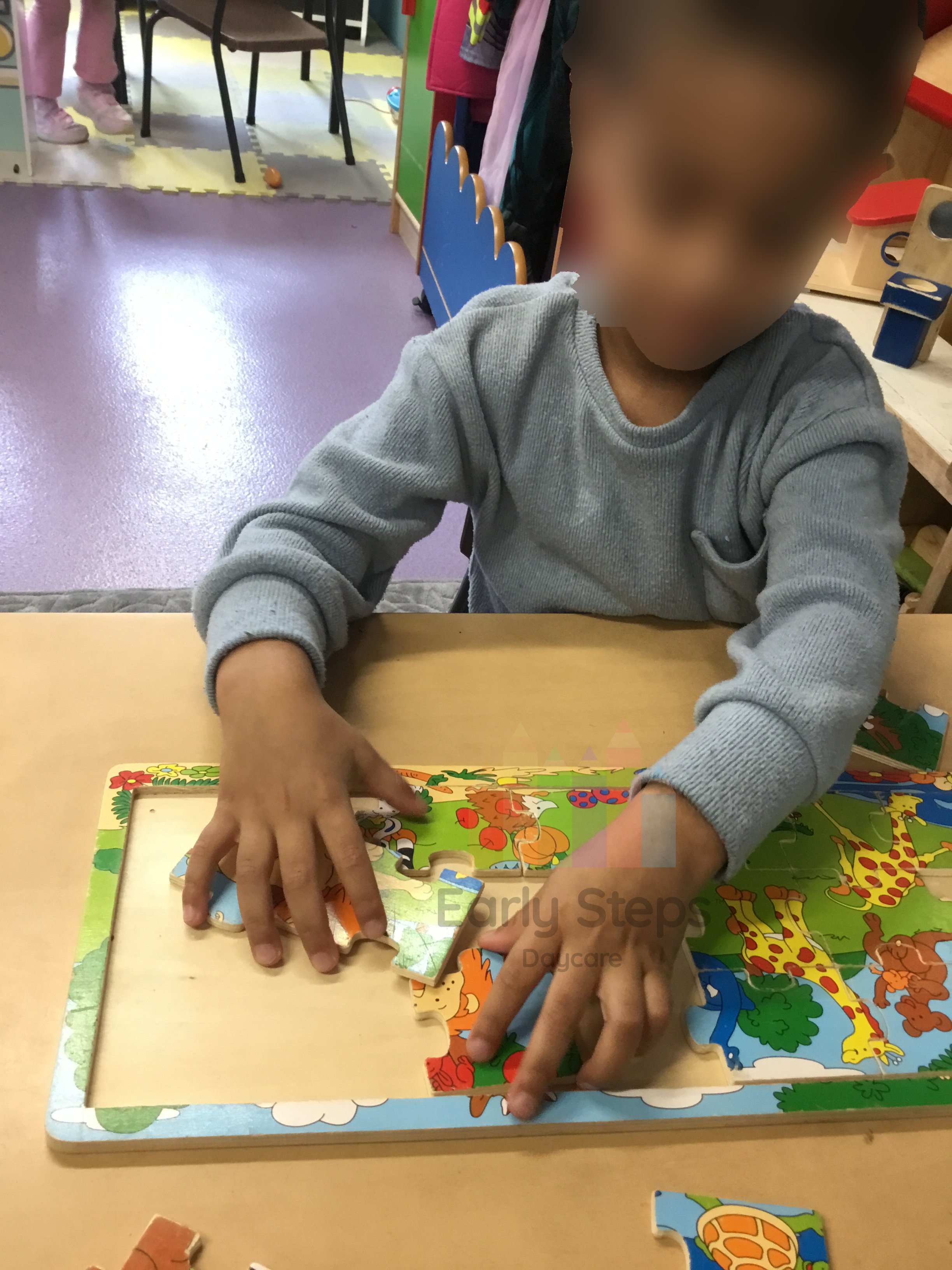 Young child focused on completing a puzzle at nursery, developing fine motor skills and hand-eye coordination.
