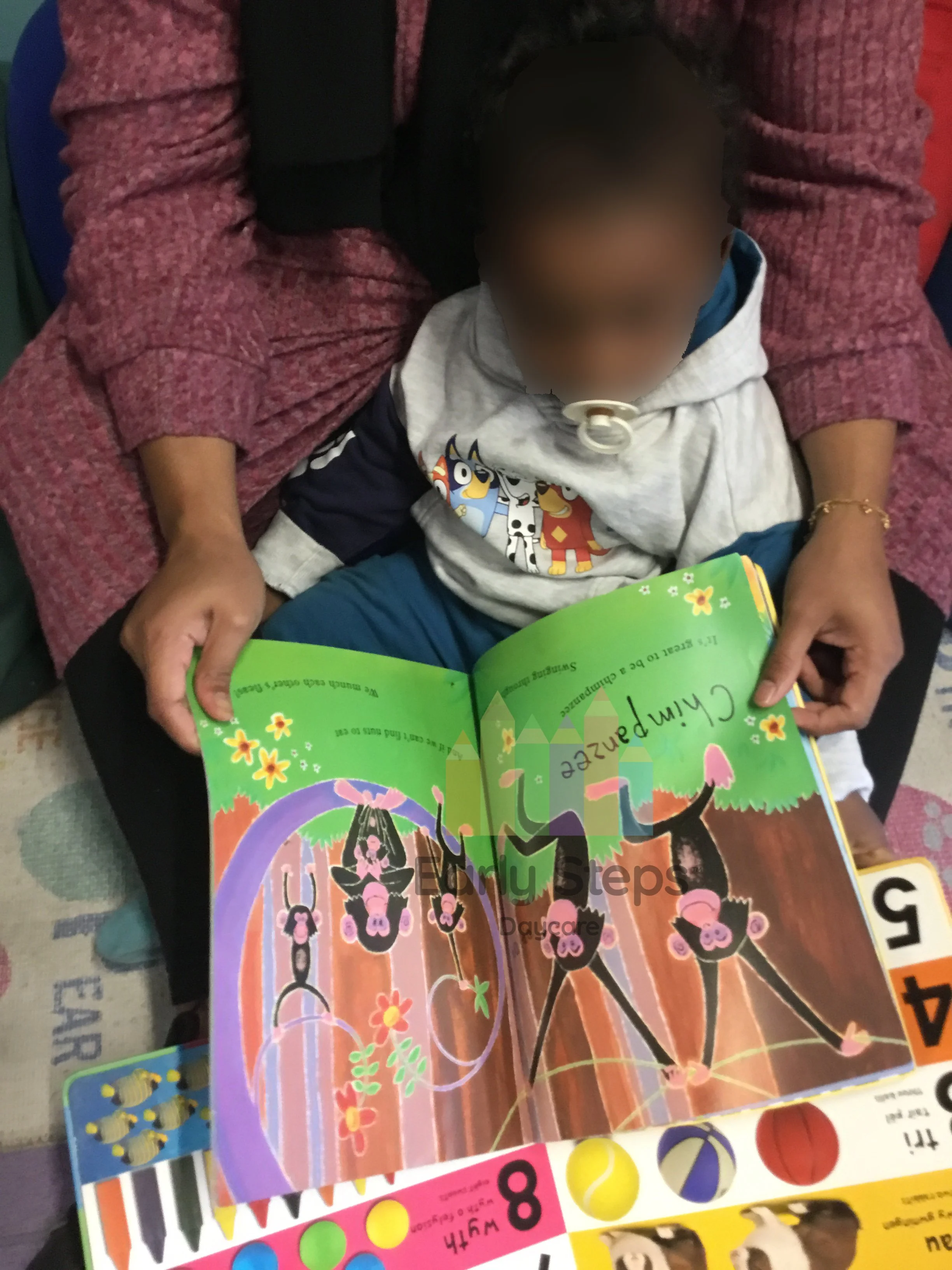 Young child independently looking at a book in the nursery book corner to support communication, language and early literacy development.