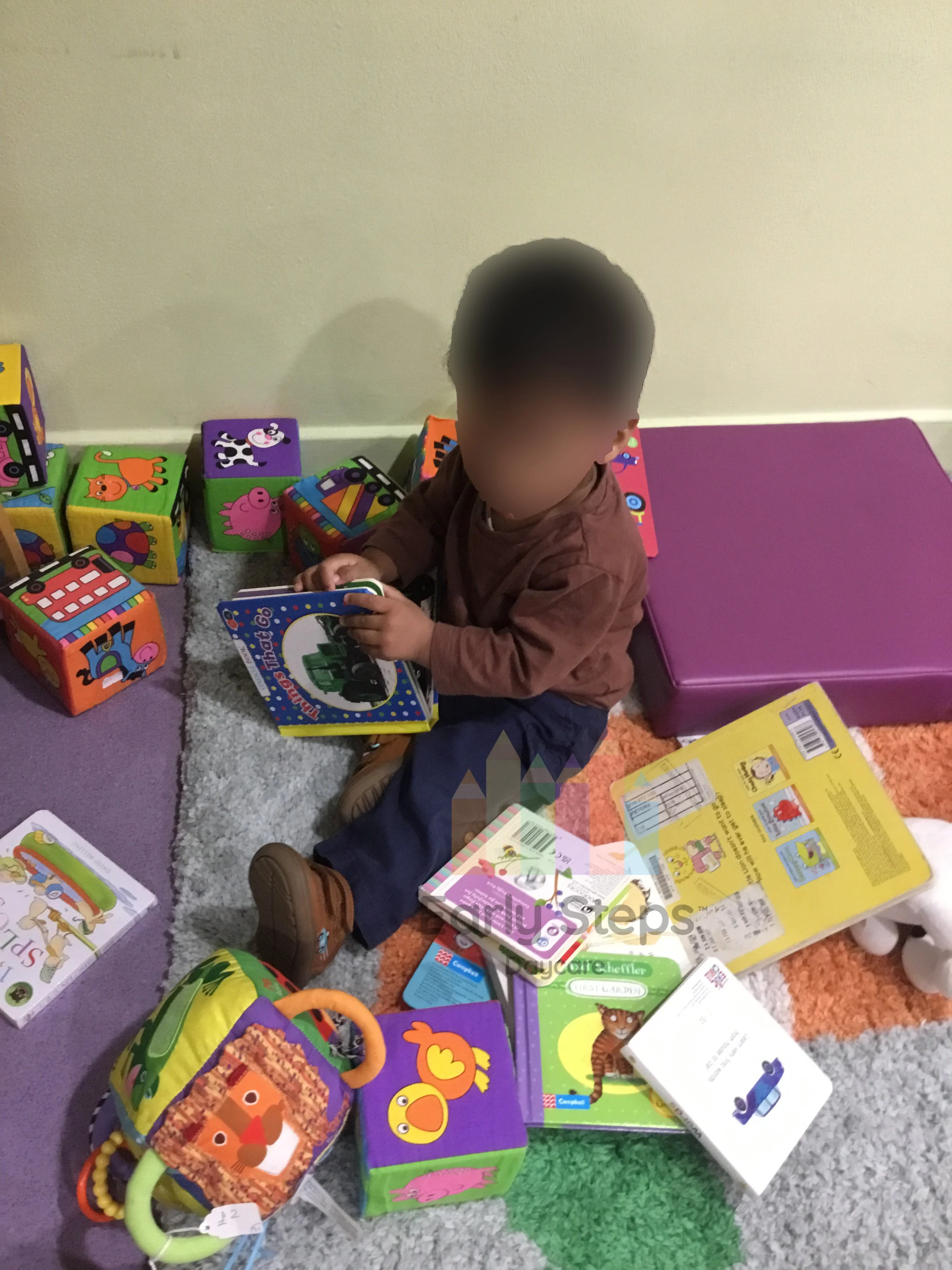 Young child reading a book at nursery to support early communication and language development.