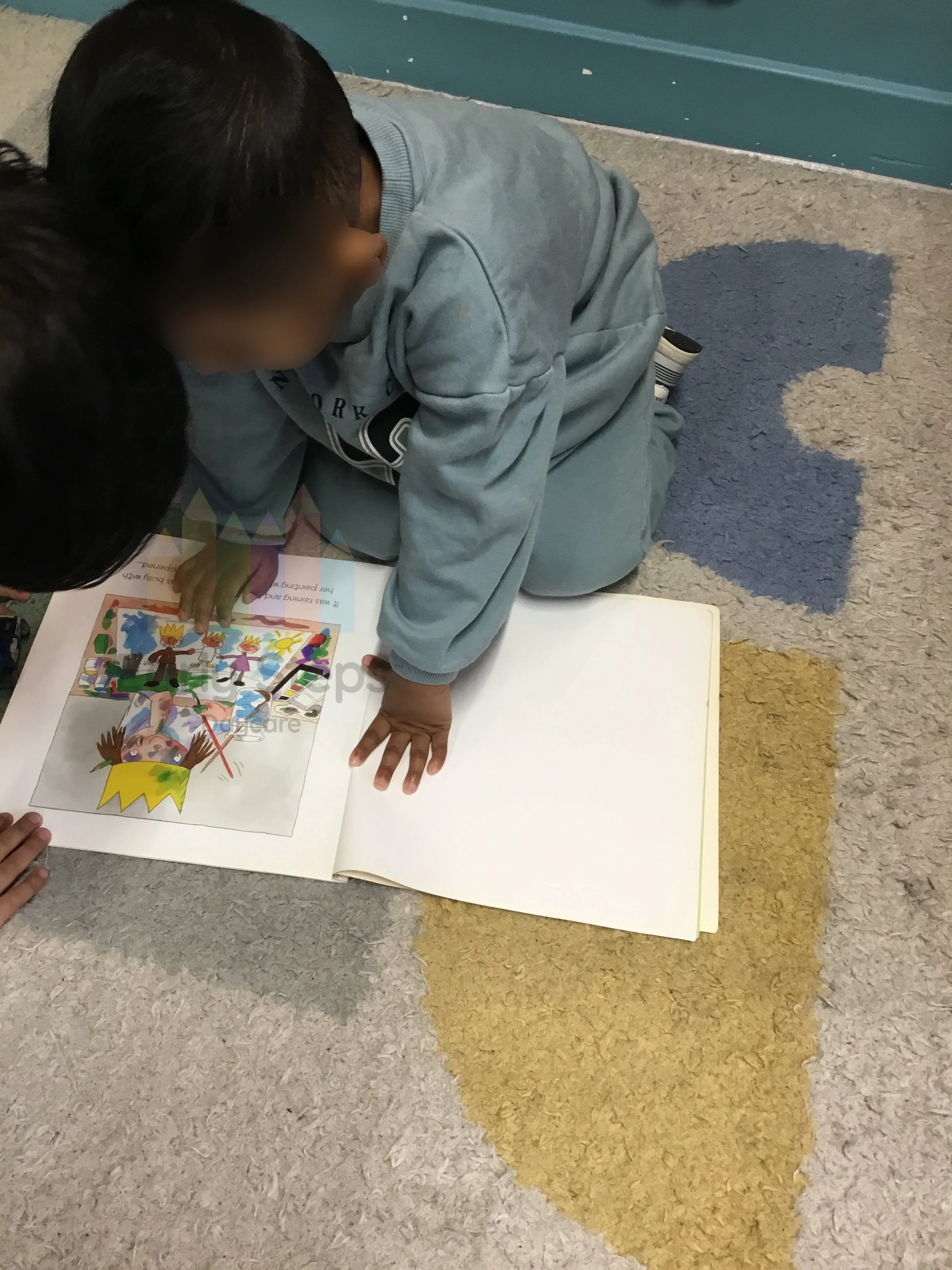 Two young children exploring a book together at nursery, supporting communication, language development and early literacy.