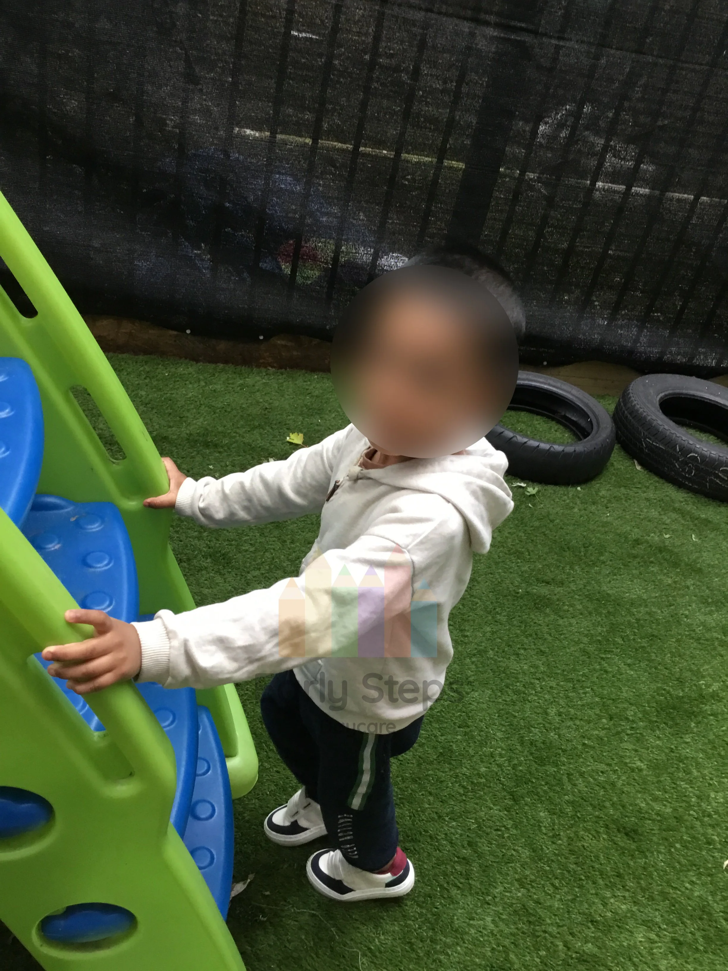 Young child climbing a slide in the nursery garden to develop balance, strength and gross motor skills.