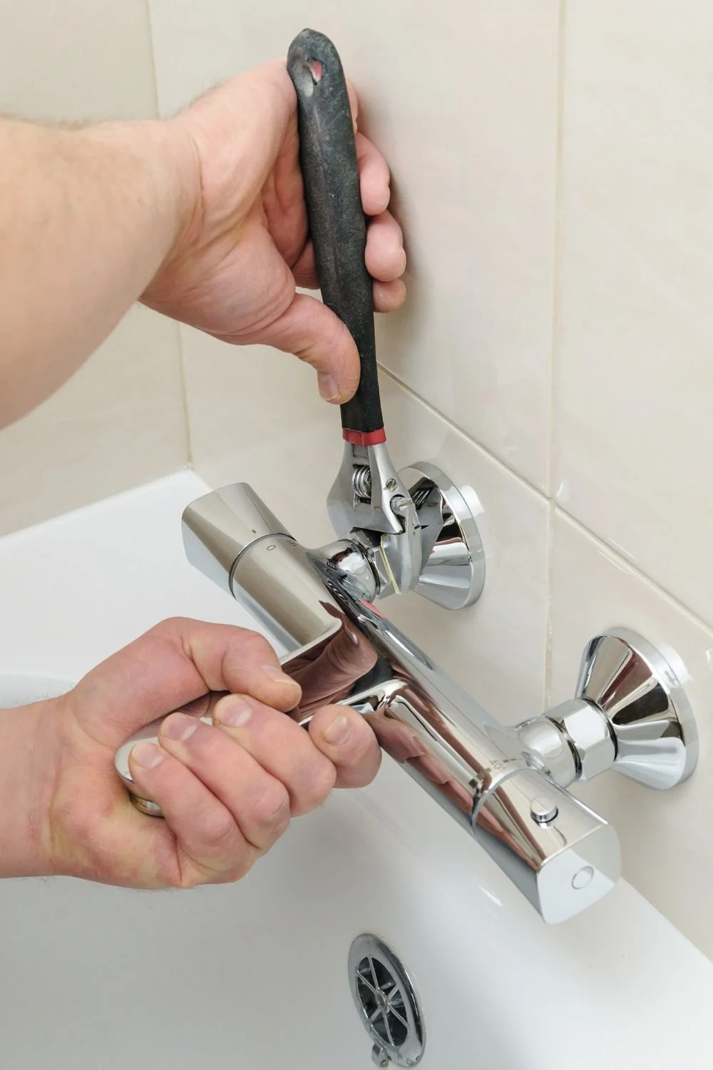 Una mano utilizza una chiave inglese per riparare il rubinetto del lavandino.