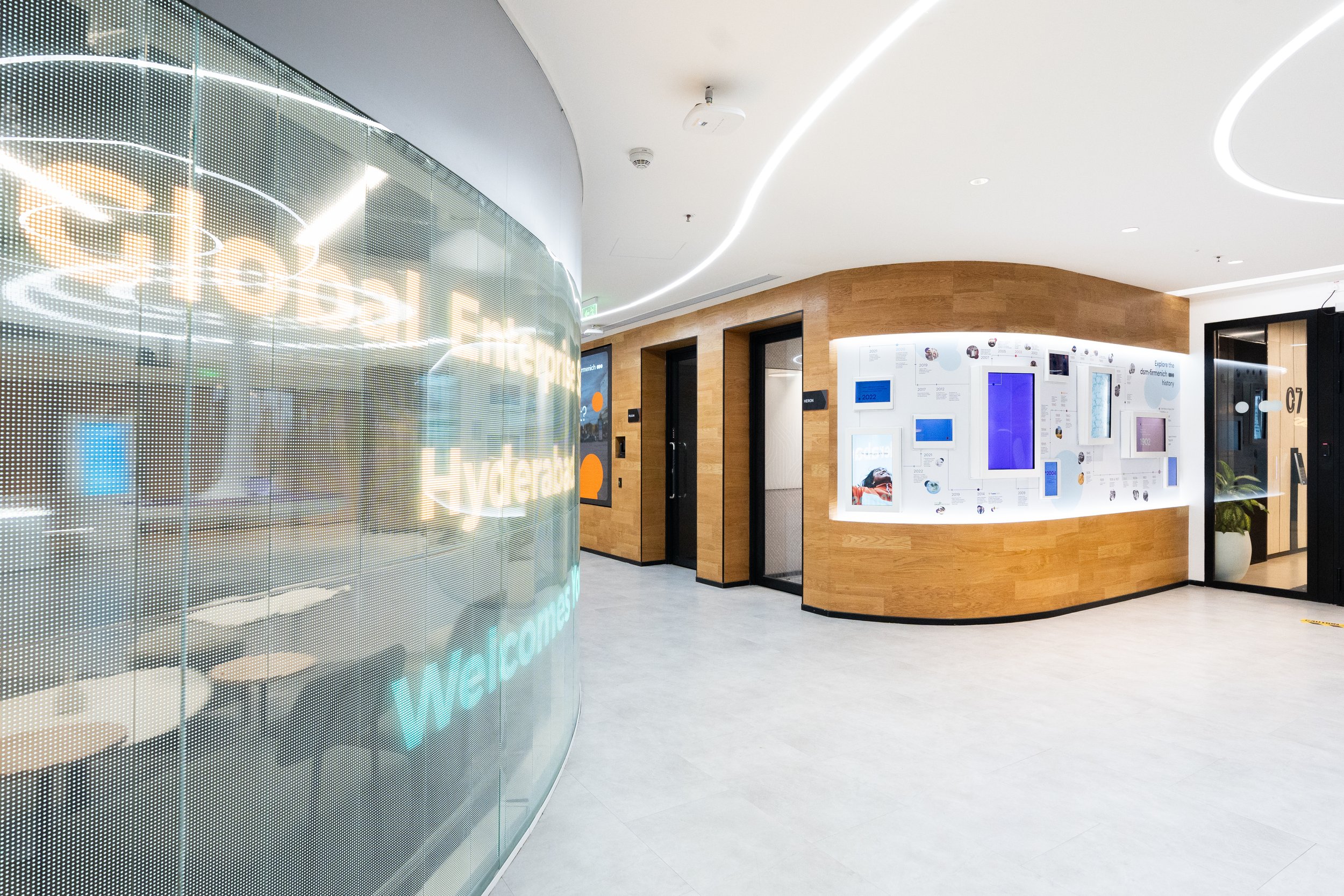 Curved digital history wall displaying a corporate timeline and archival content within a modern interior environment