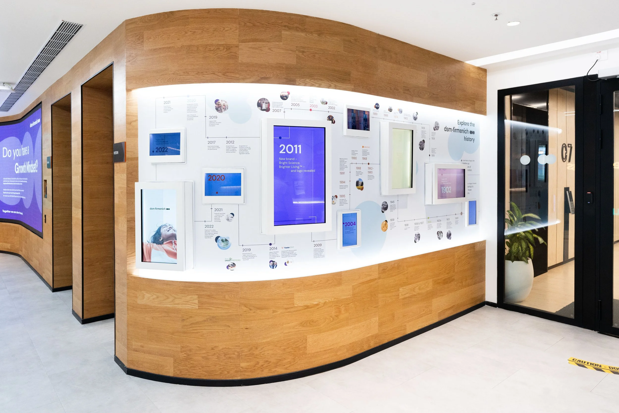 Interactive digital history wall showcasing a company timeline with integrated displays and content panels within a corporate experience centre.