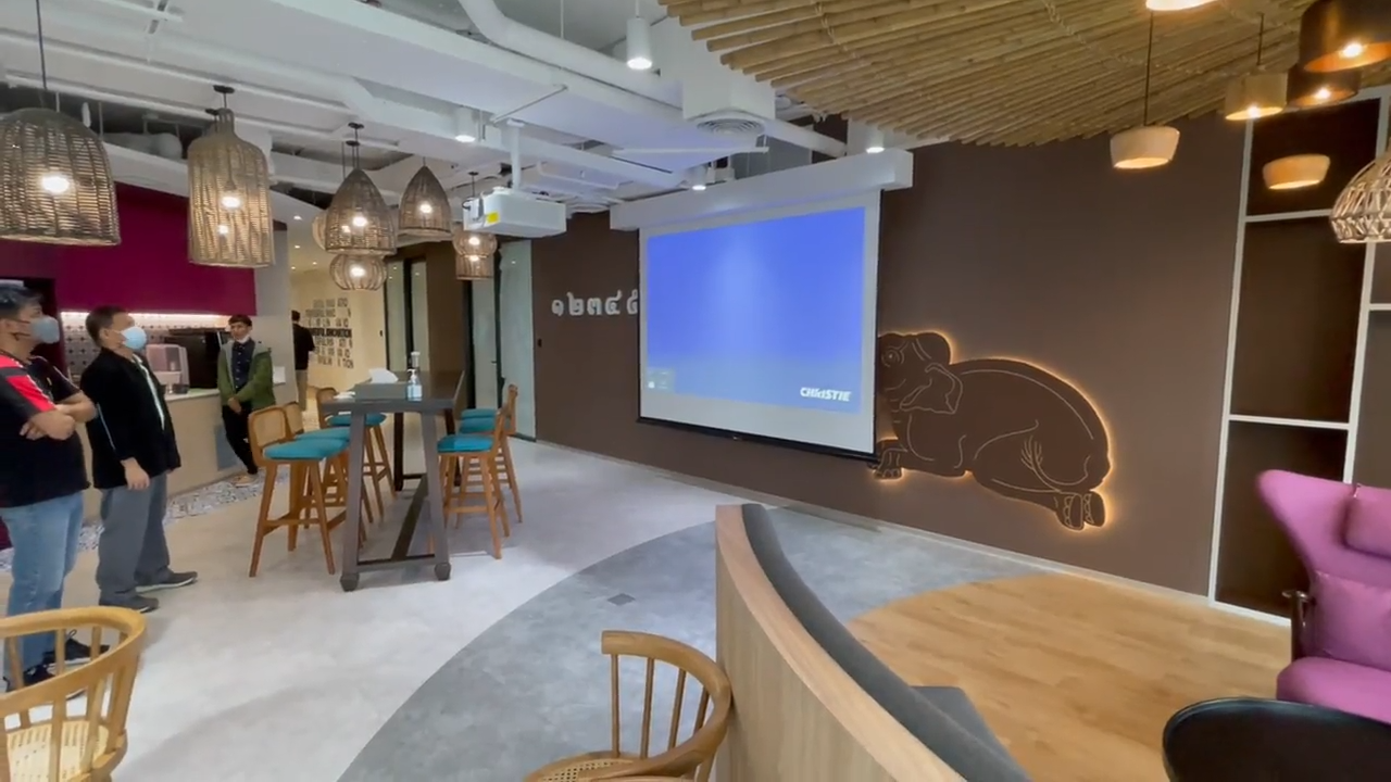 Informal collaboration space within a Thailand BPO production floor featuring projection, casual seating and audiovisual presentation technology.