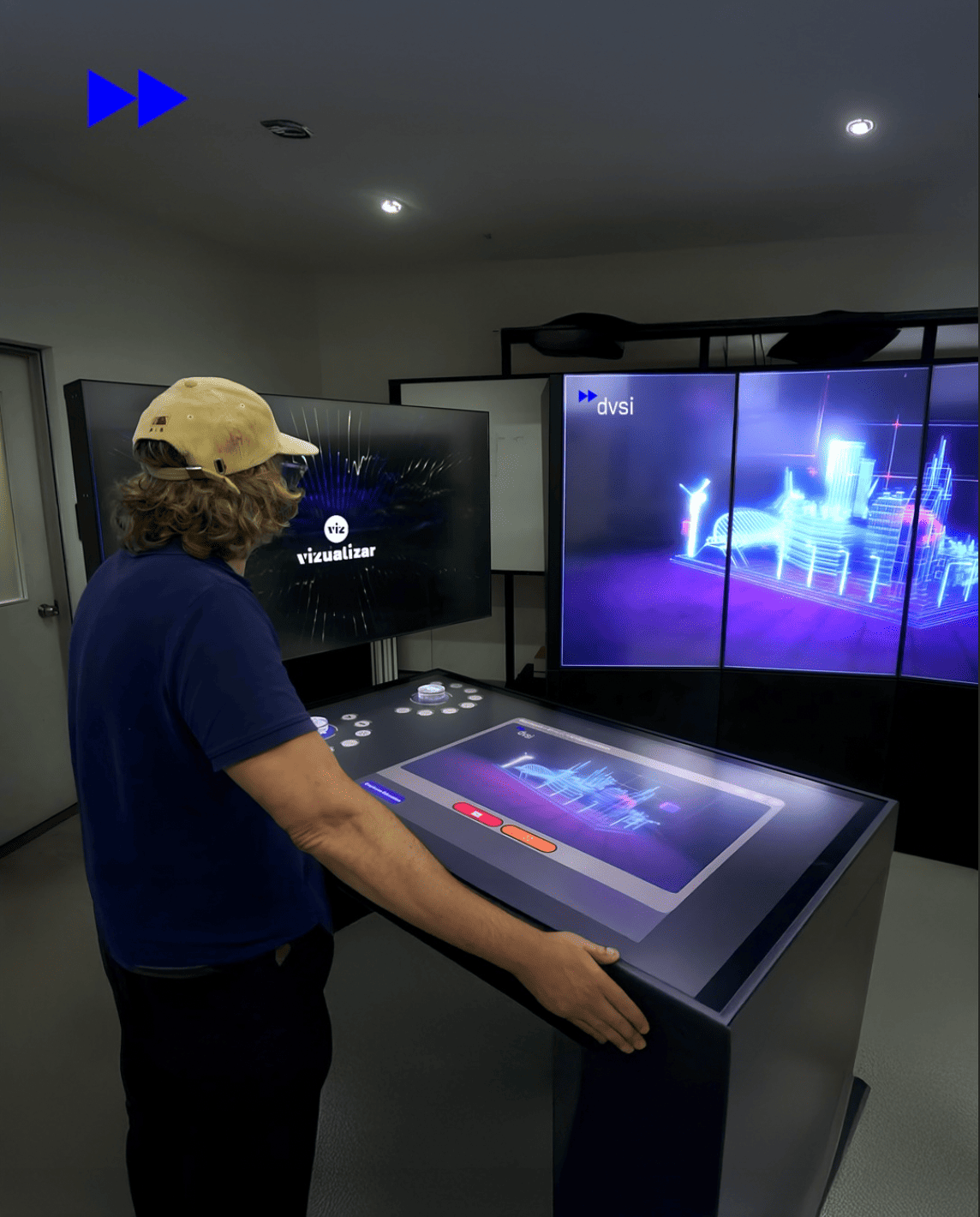 Person interacting with an object recognition table and large digital displays to explore 3D data visualisation and interactive content within an experience centre environment