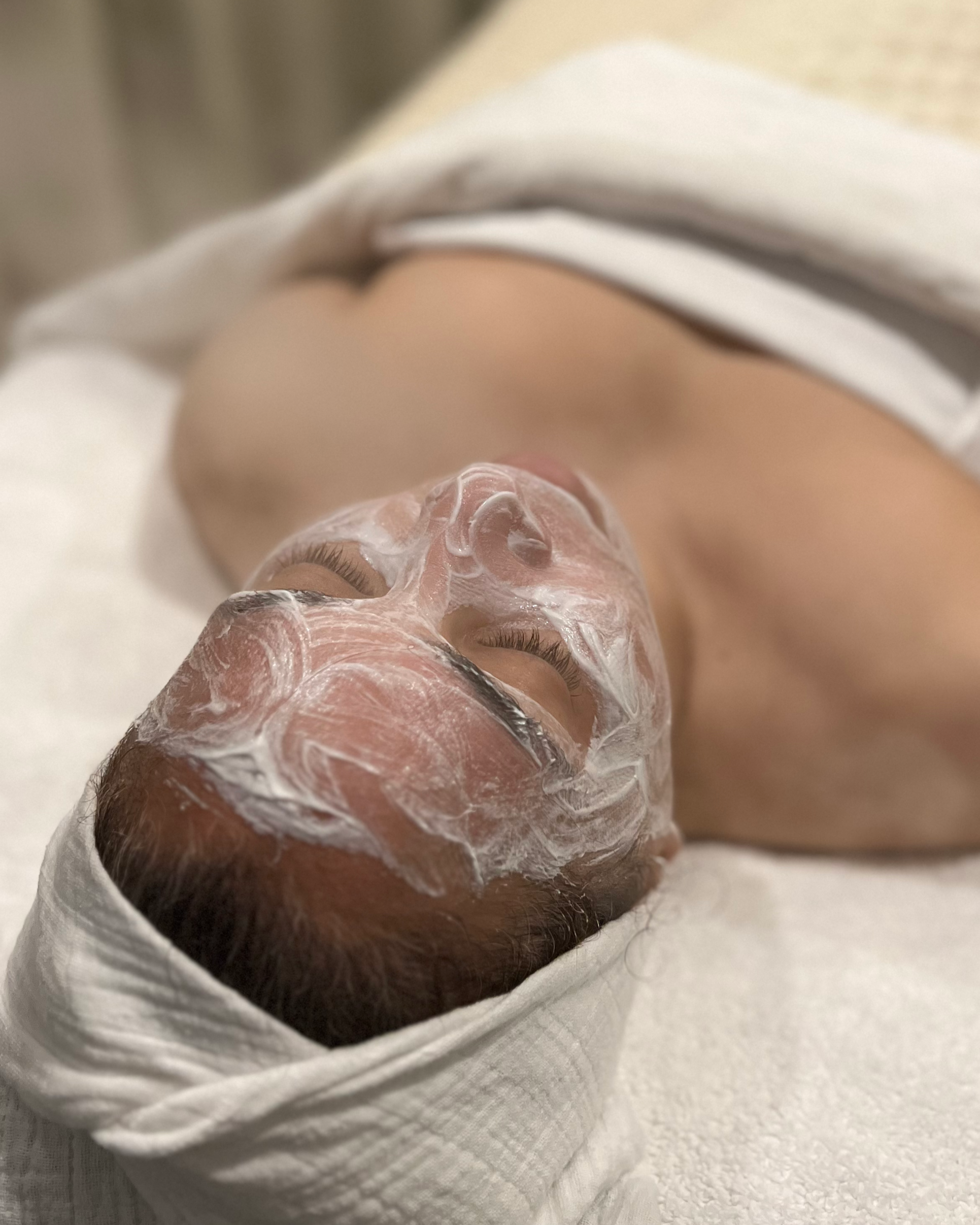 Client lying on a treatment bed with an Environ Cool Peel applied to her face