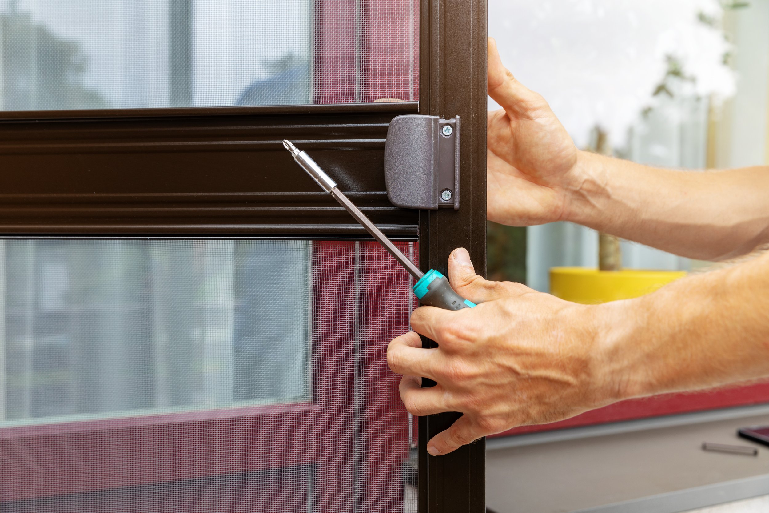 red screen door, philips head screw drive, hands fixing the door
