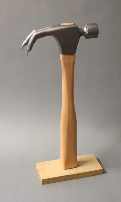 A hammer with a wooden handle displayed on a wooden stand.