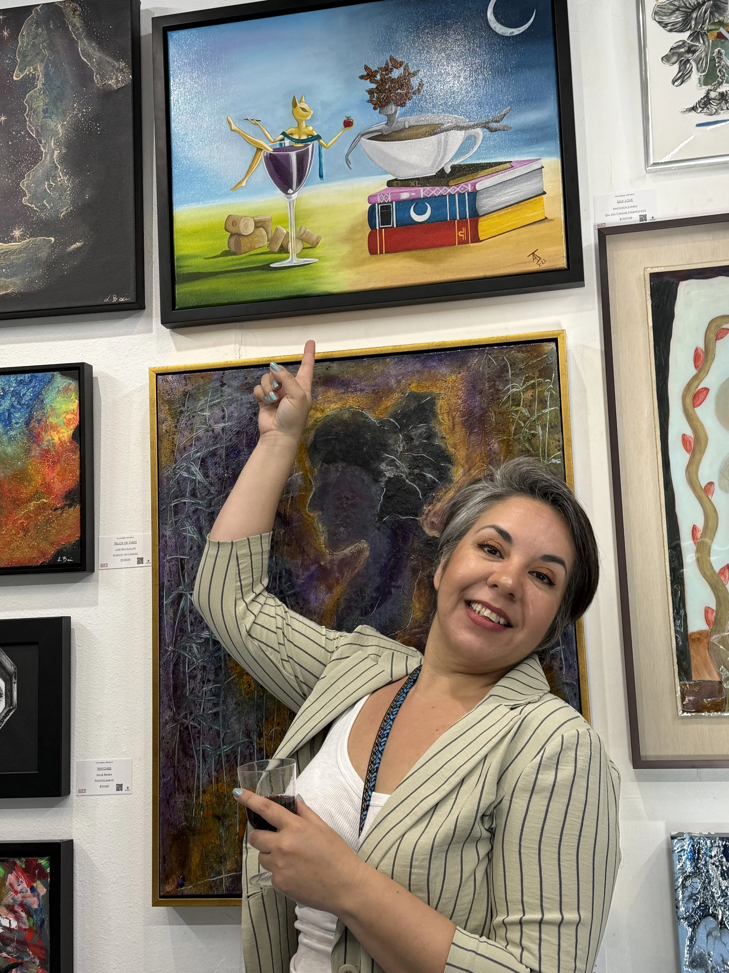 A woman smiling and pointing at a colorful surreal painting on a gallery wall, holding a glass of red wine.