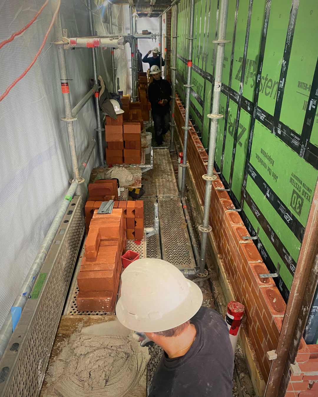 Johnson Playfair masons Kevin, Celeste, and Brent working on a masonry veneer addition with heritage-match bricks in Toronto.