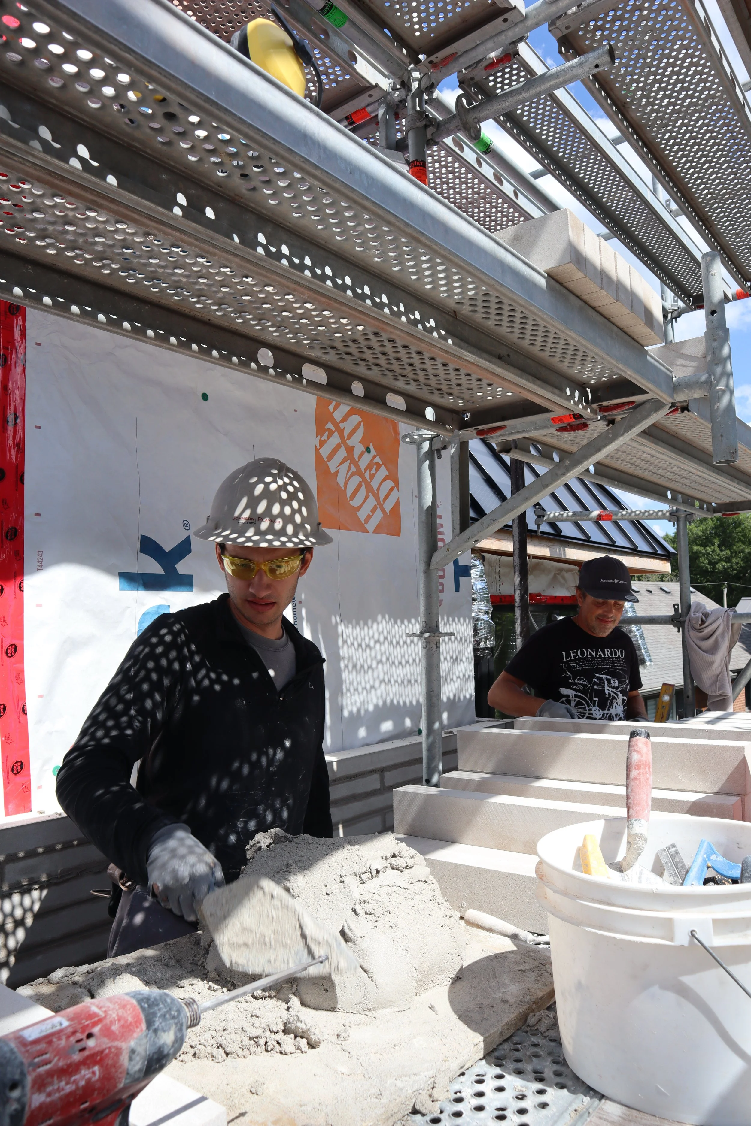 Johnson Playfair masons Davis  and Eric installing custom-order linear limestone brick on a new home's chimney in Toronto.