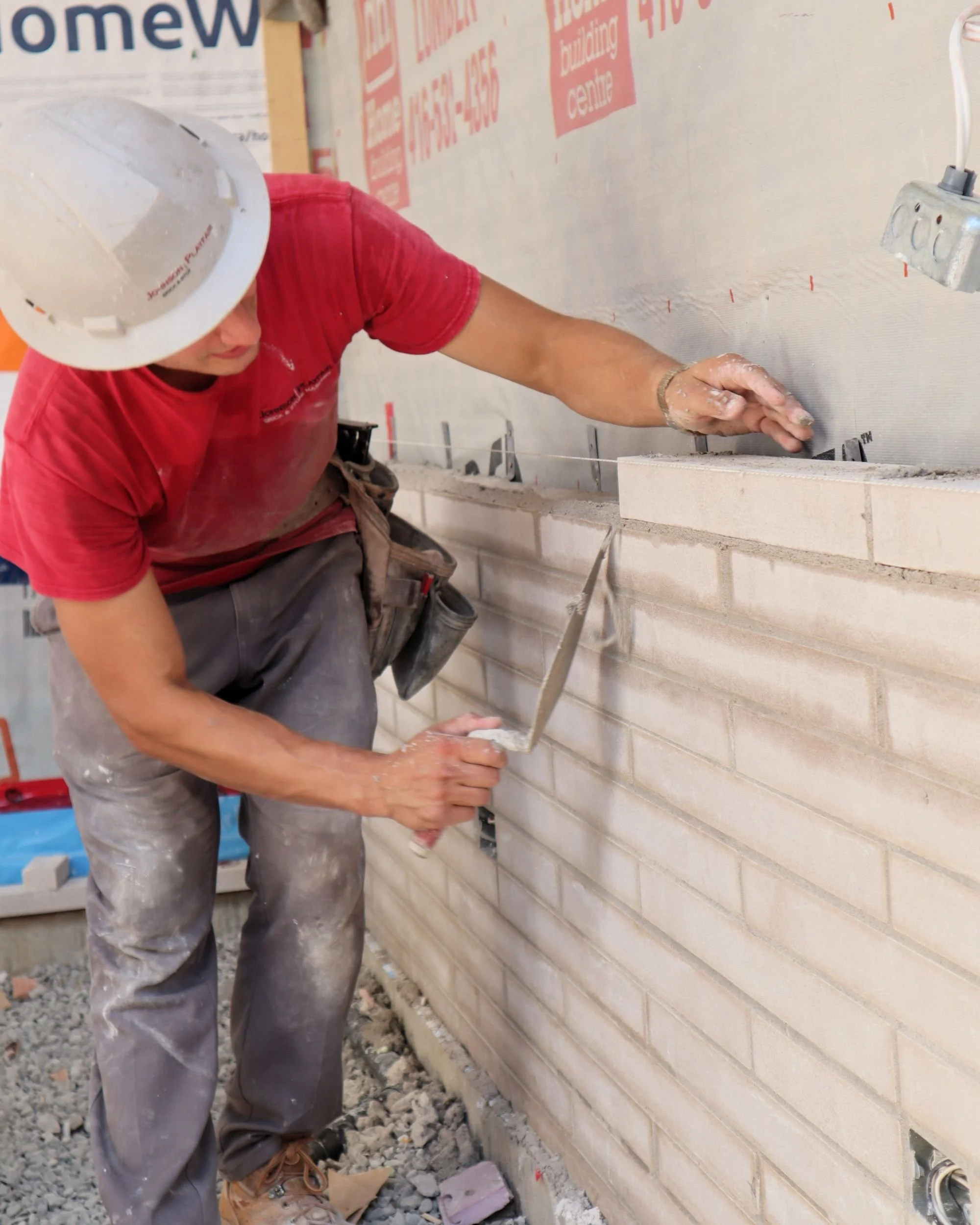 Johnson Playfair mason Davis installing custom-order linear limestone brick on a new home in Toronto.