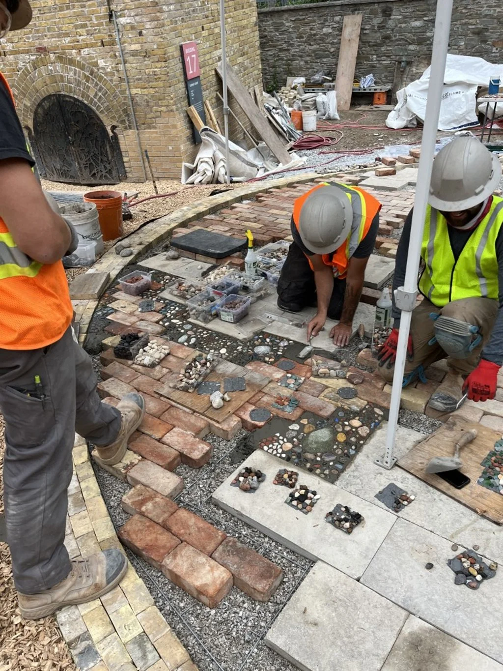 Johnson Playfair masons installing a masonry art pavilion at Evergreen Brickworks in Toronto, using reclaimed brick and local stone mosaics.