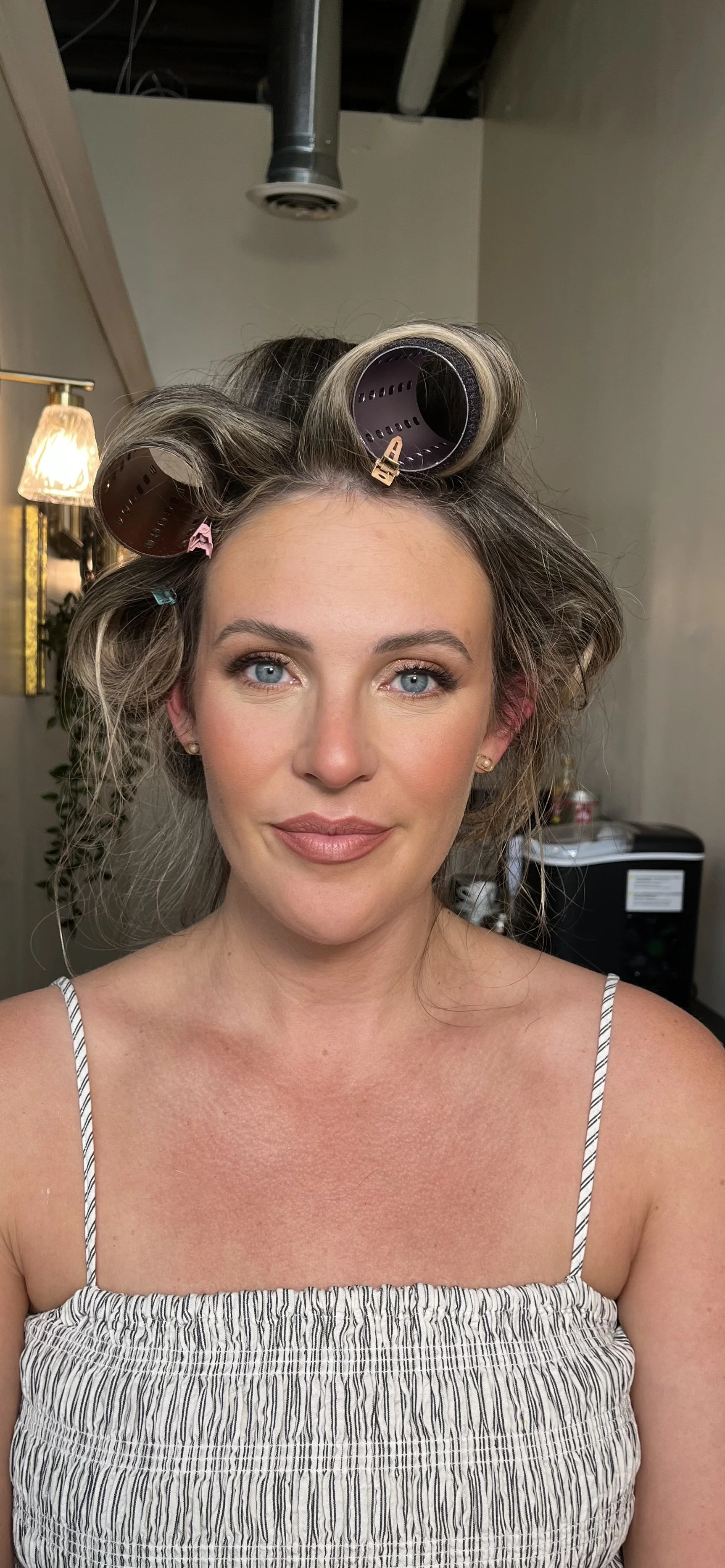 Caucasian woman with rollers in her hair, who got a beautiful soft glam makeup style with neutral colors done by Erica K.