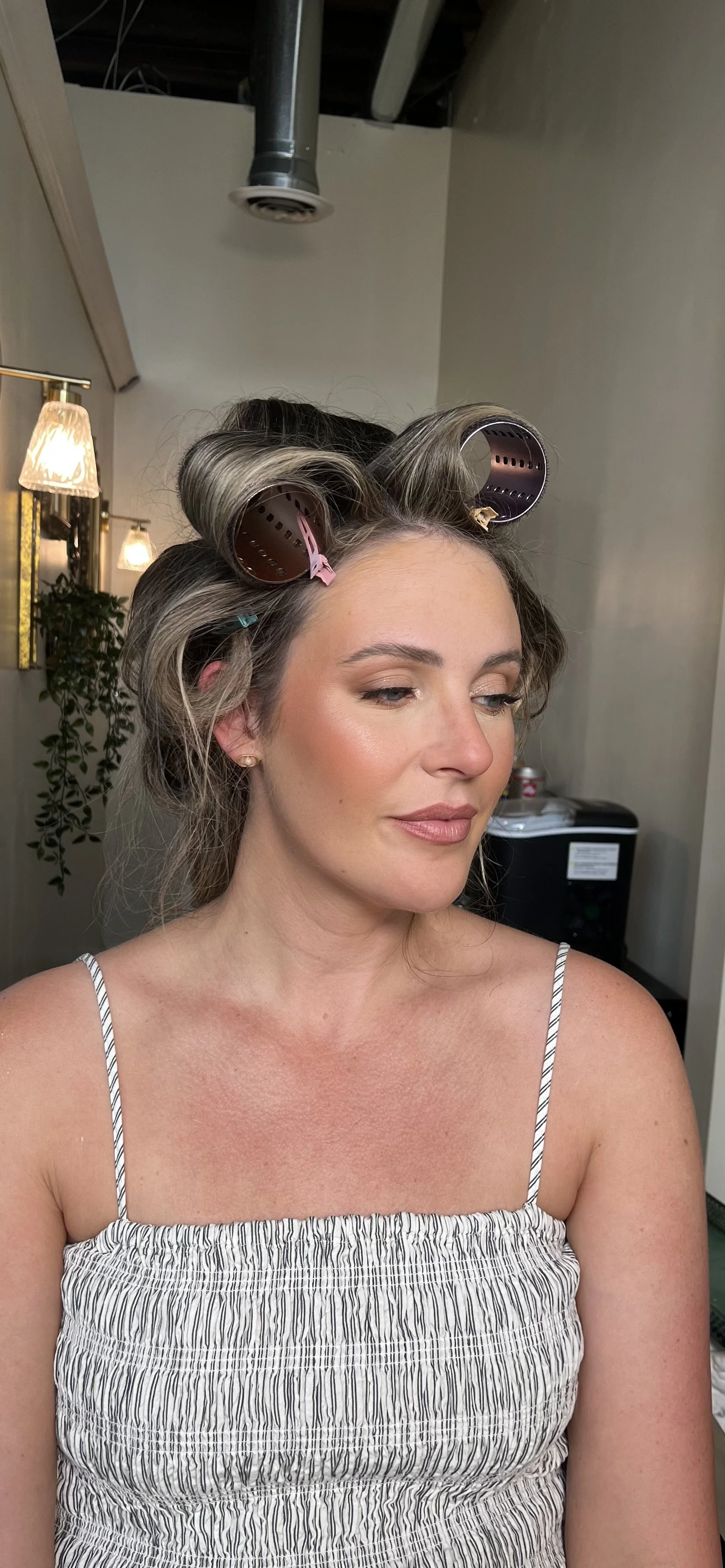 Caucasian woman with rollers in her hair, who got a beautiful soft glam makeup style with neutral colors and shimmers done by Erica K.