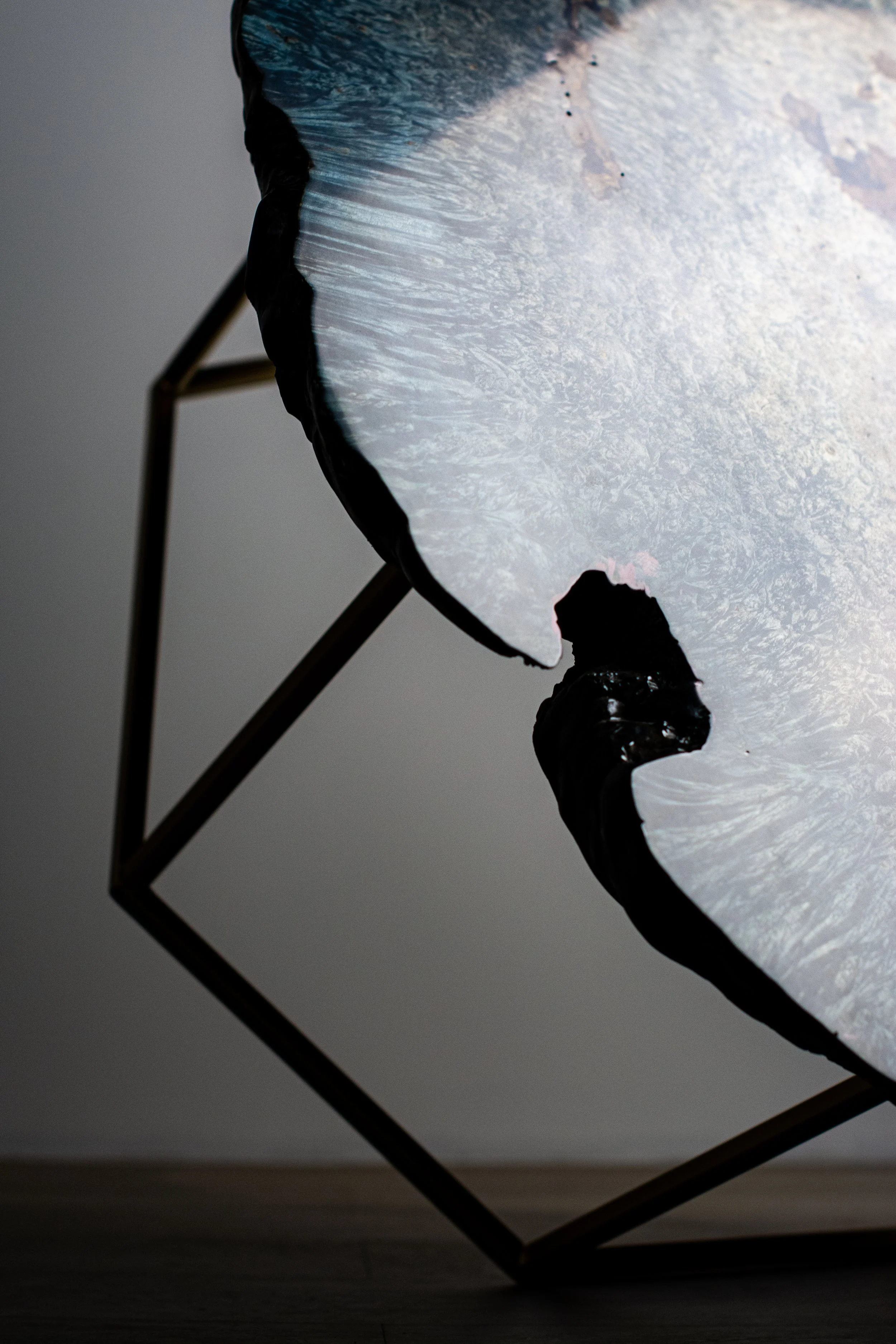 Close-up of a broken or shattered LED panel light, with visible cracks and a dark background.
