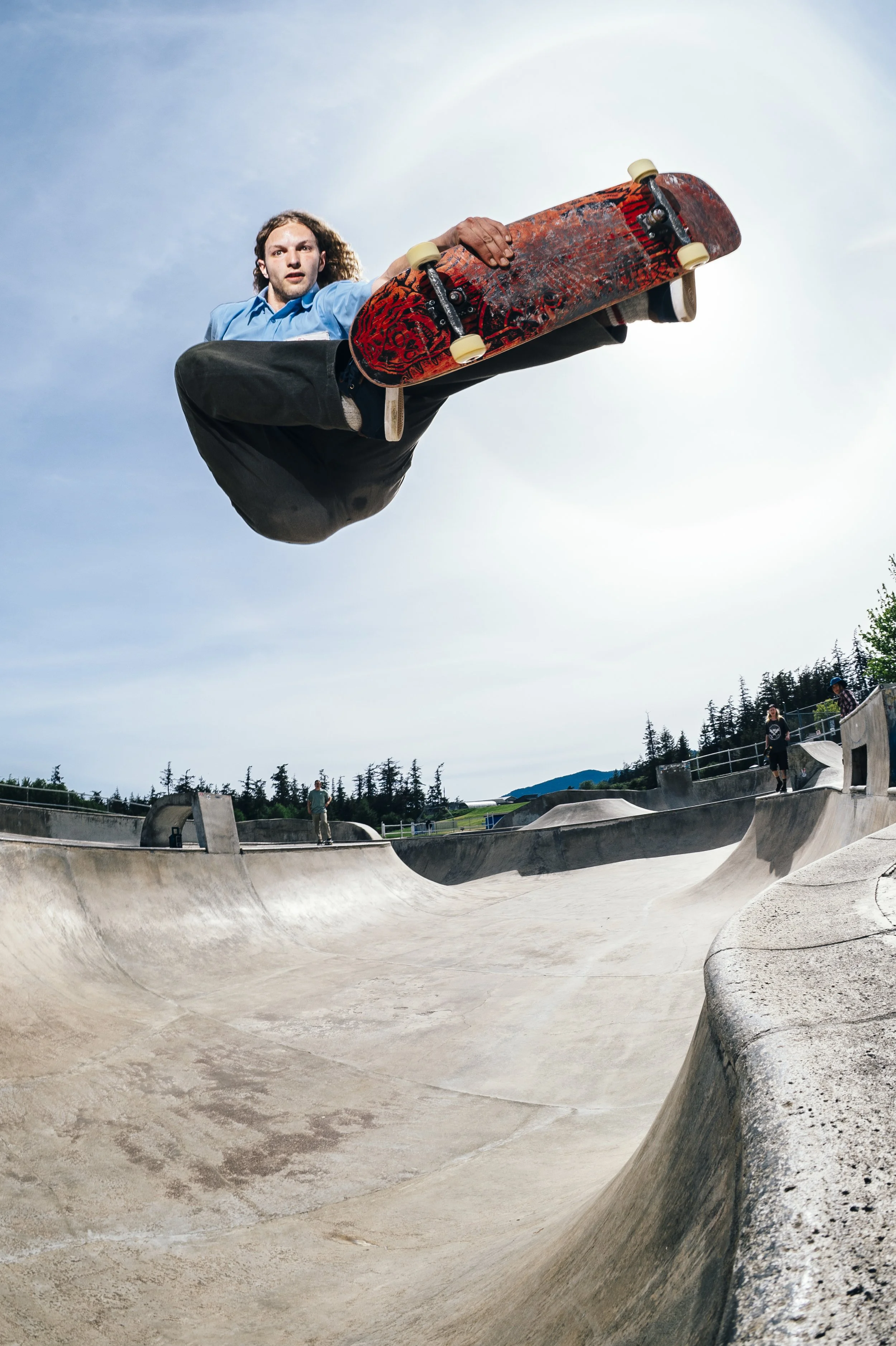 Skateboarder performing an aerial trick at a skate park.