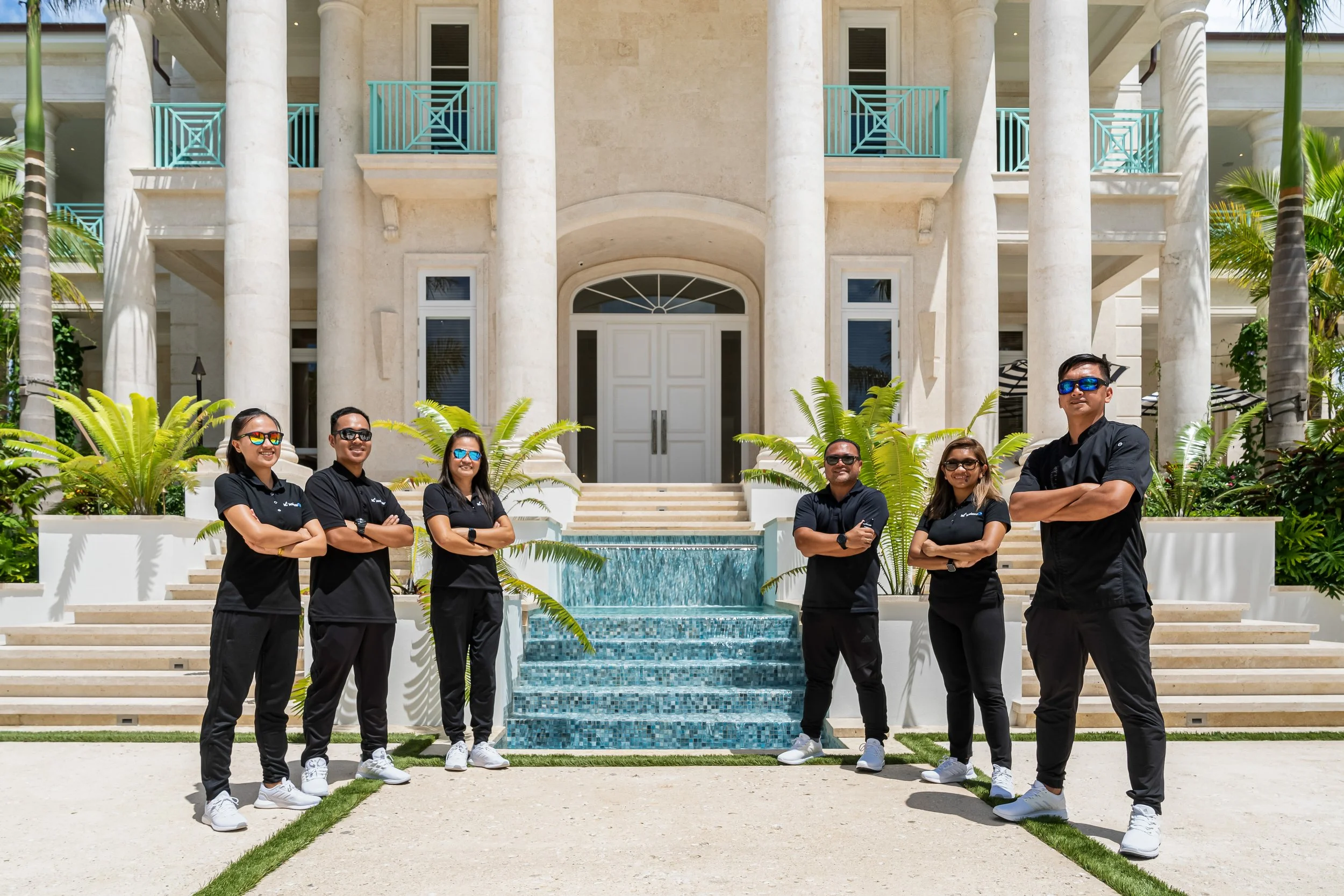 Vill staff standing in front of a beautiful villa - Our Services - Water's Edge Villa