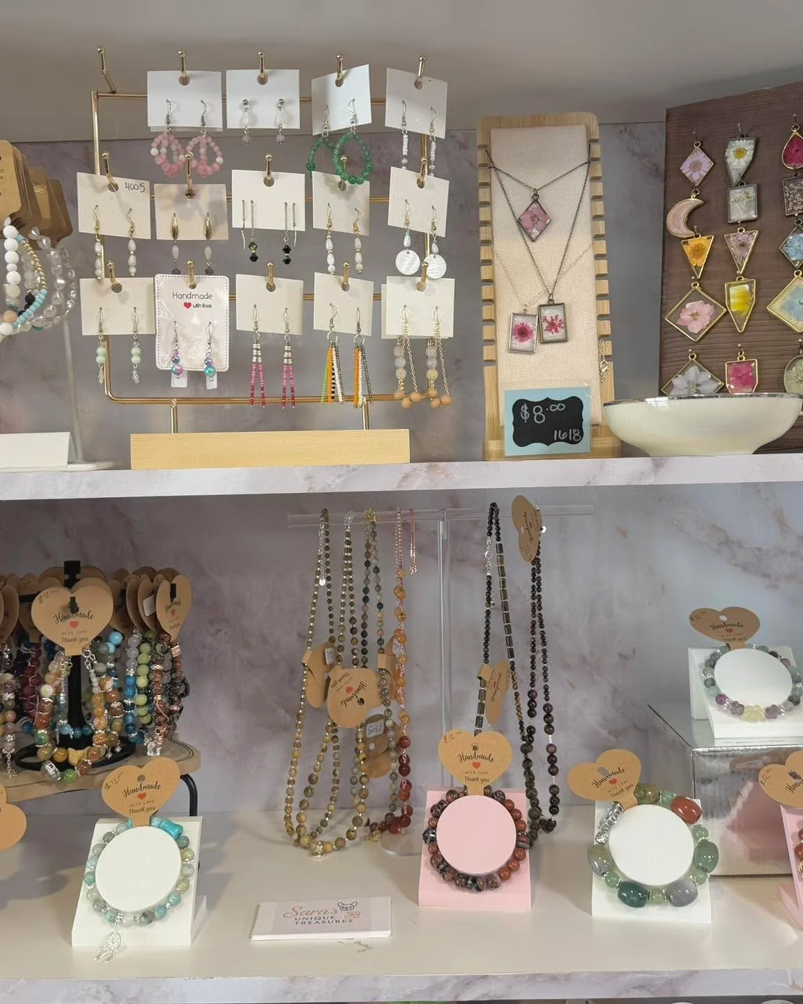 There's a whole lot of sparkle on our shelves right now.

Handcrafted earrings, beaded bracelets, gemstone strands, and pressed flower pendants, all made by hand and all one of a kind. Stone bracelets with the meaning of each stone printed right on t