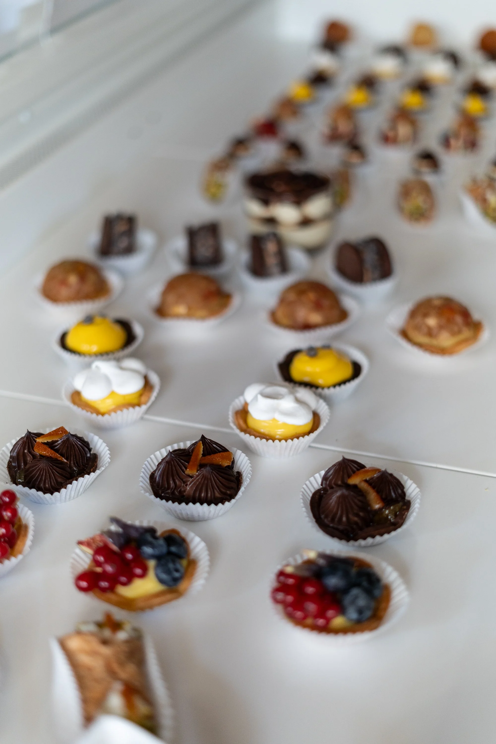 Verschiedene kleine Desserts und Pralinen auf einer weißen Oberfläche.