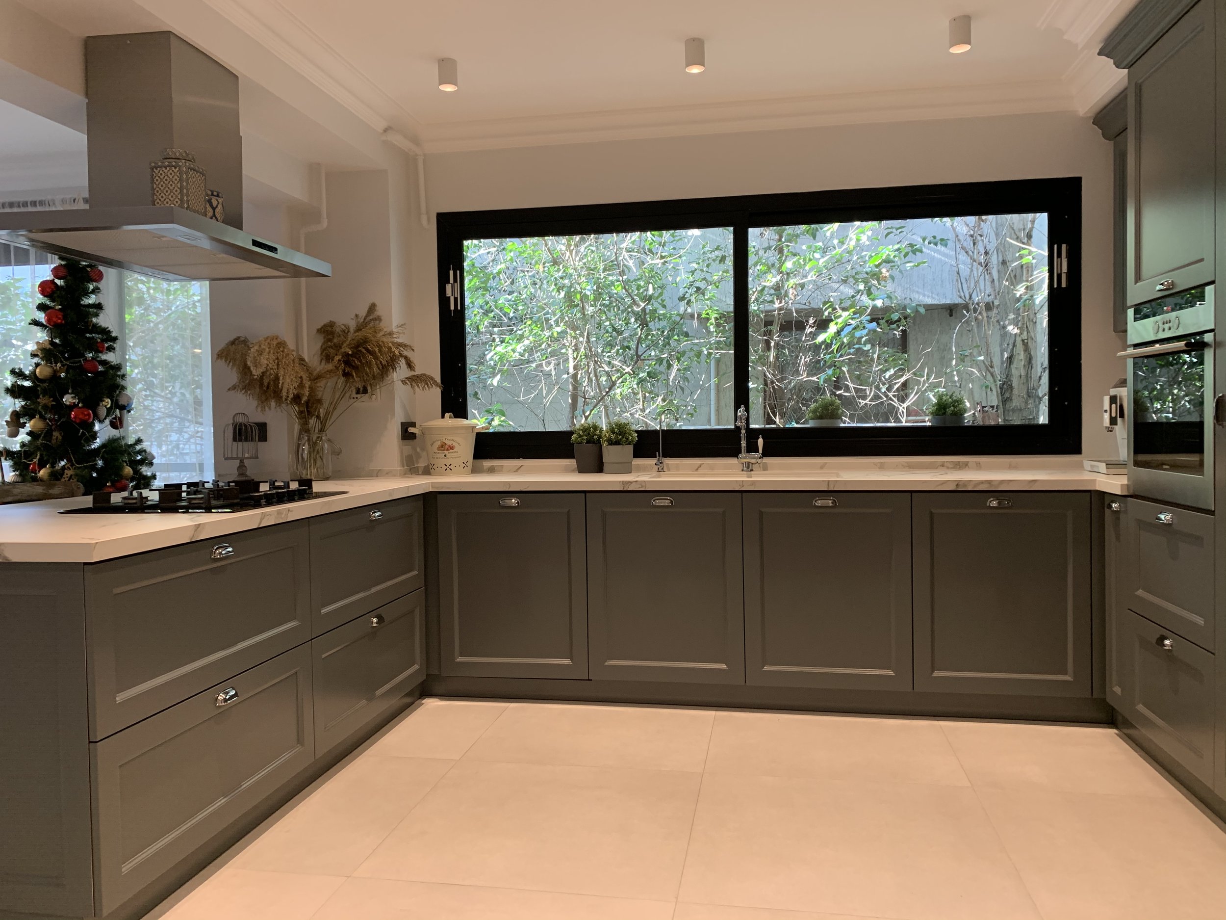 A luxurious modern open concept kitchen boasting quartz countertops, custom serene hunter forest green cabinetry, and high-end stainless steel appliances.