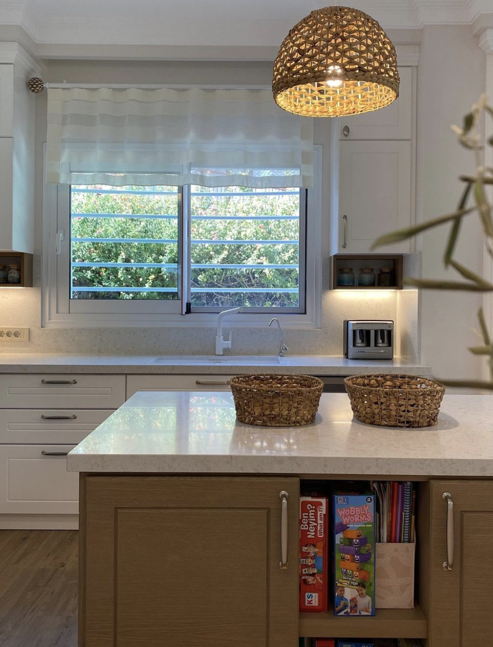 View from the central island of an open-concept modern kitchen, white and dark mustard yellow cabinetry, hidden lighting under cabinets and contemporary pendant lighting.