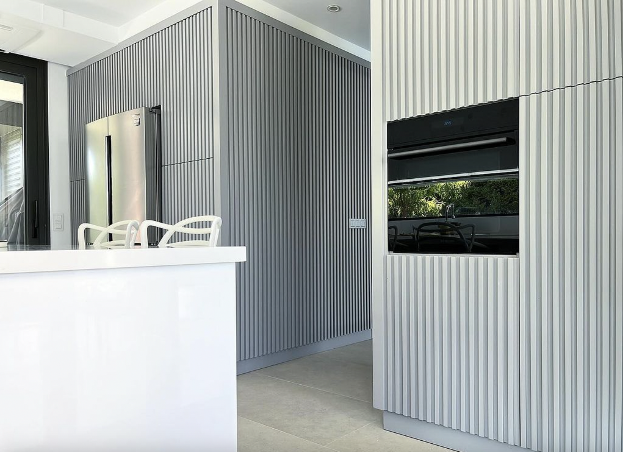 View from the wall cabinets of a minimalist kitchen with clean lines, light blue grey cabinets, white quartz countertops, and integrated appliances for a seamless look.