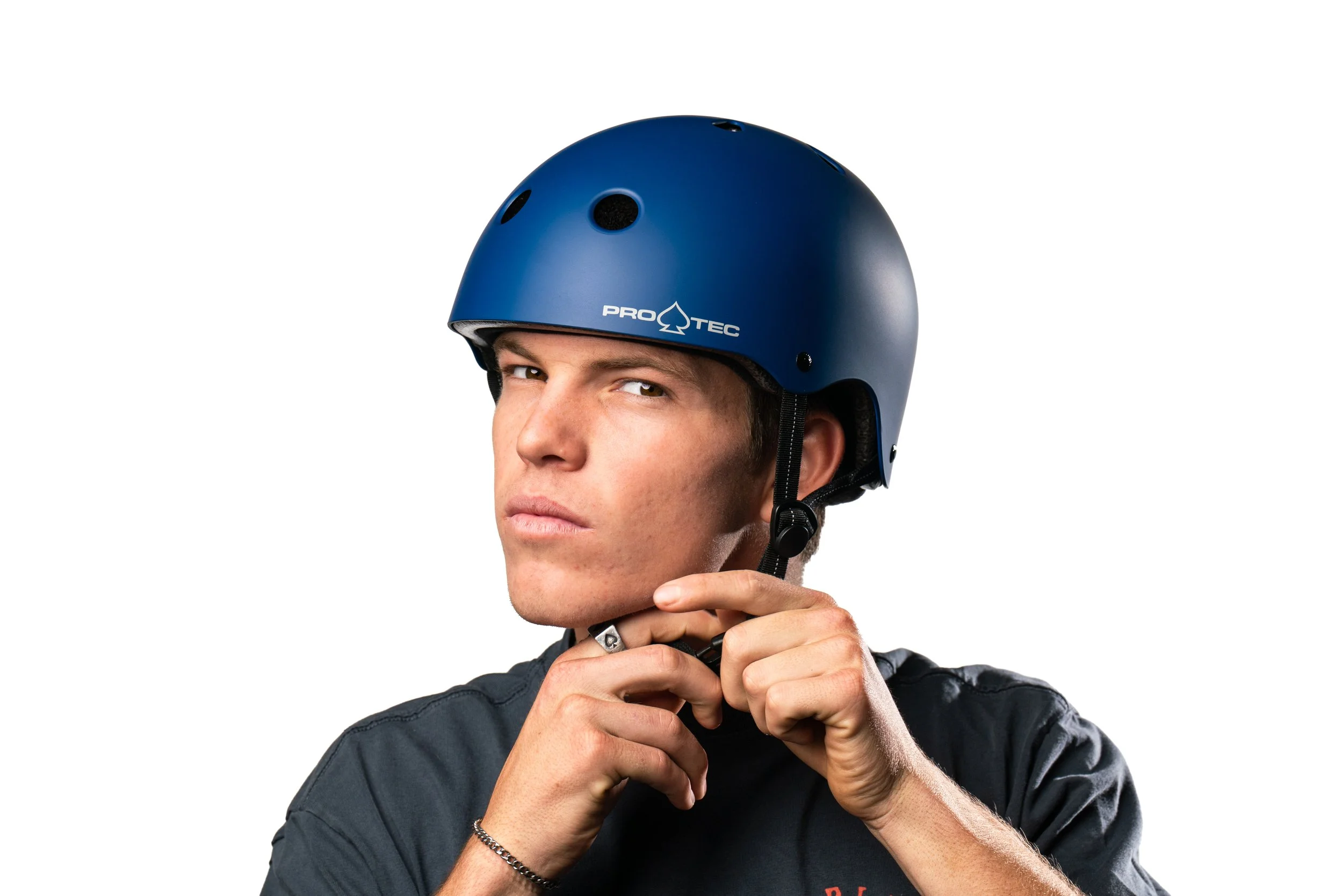 Young man wearing a blue helmet, adjusting the chin strap, against a white background.