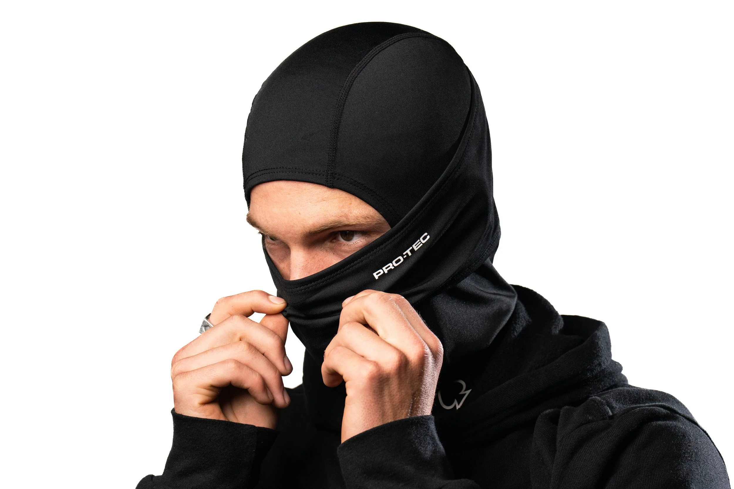 A person wearing a black ski mask and black clothing, adjusting the mask over their face.