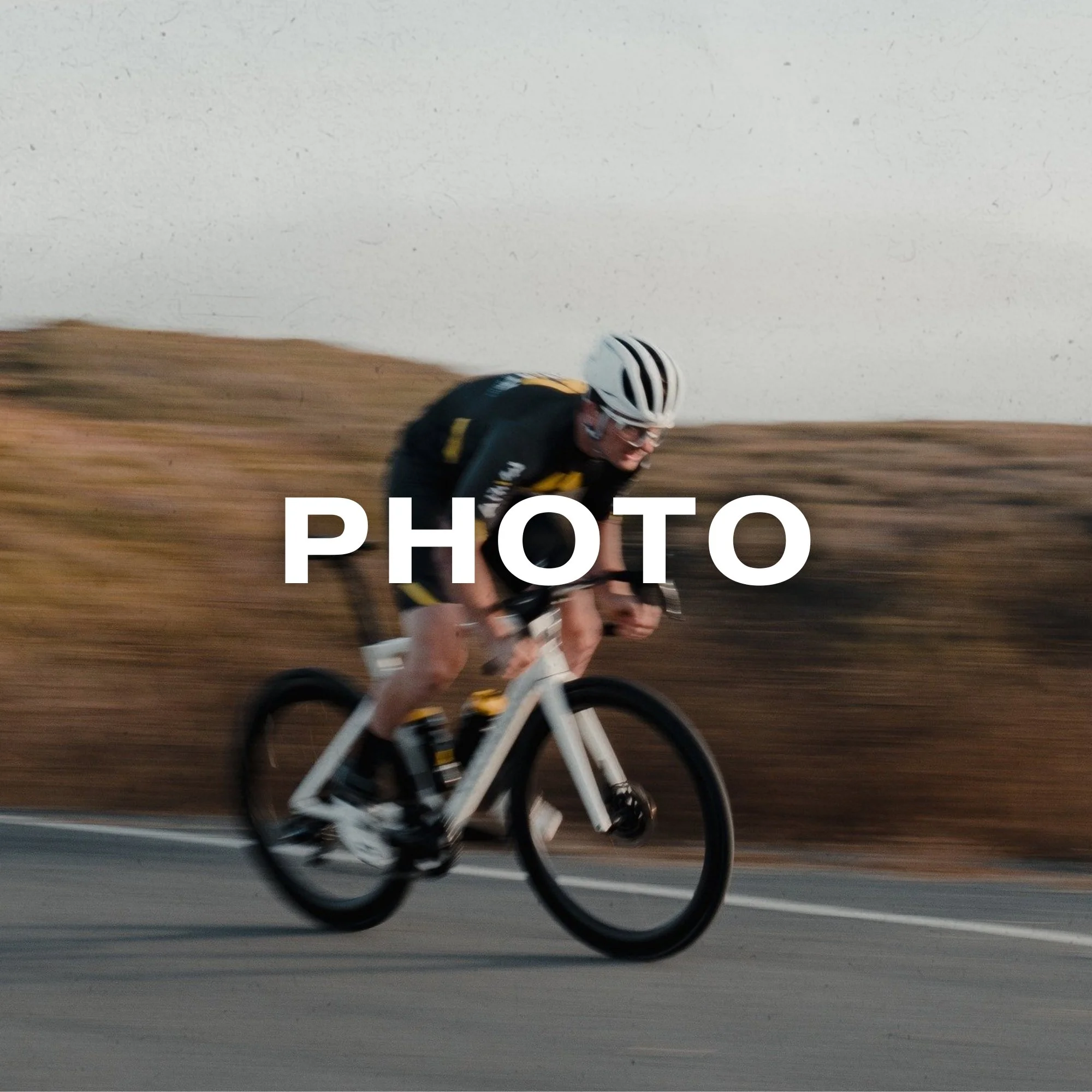 Cyclist in black and yellow jersey riding a white bike on a road with a blurred background